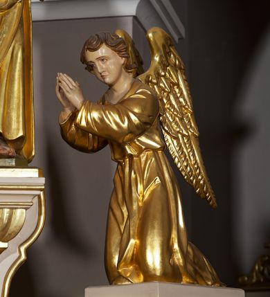 Zdjęcie nr 13: Ołtarz w formie rzeźbionej, ażurowej ramy na trójstopniowym cokole, z prostopadłościenną mensą z antepedium dekorowanym kwadratowymi płycinami z motywem czworoliścia. Na nim prostopadłościenne tabernakulum z drzwiami w kształcie stojącego prostokąta dekorowanymi koszem z chlebem, rybami i chrystogramem. Środkowa część podstawy wypełniona płycinami w kształcie leżących prostokątów z plakietami roślinnymi. Na jej zewnętrznych częściach posadowiono figury klęczących aniołów. Najwyższy stopień węższy, trójosiowy, o osiach zewnętrznych wysuniętych, flankowany konsolami z rzeźbami Matki Boskiej po lewej stronie i św. Jana Ewangelisty po prawej. Centralnie umieszczona rama ujmuje pole w kształcie serca, na tle którego jest eksponowany krucyfiks. Ażur tworzy wić winnej latorośli z kiśćmi winogron, a w nią wkomponowane jest siedem postaci aniołów trzymających banderole z ostatnimi słowami wypowiedzianymi przez Chrystusa wiszącego na krzyżu. Od góry: „Pragnę”, „Niewiasto! Oto syn Twój”, „Oto matka twoja”, „Ojcze odpuść im, / bo nie wiedzą co czynią”, „Zaprawdę powiadam tobie / dziś jeszcze będziesz ze Mną w raju”, „Spełniło się! / Ojcze w ręce Twoje oddaję ducha mojego”, „Boże mój Boże mój / czemużeś mnie opuścił”. Struktura w kolorze kremowym, profile, detale i ornamenty złocone; banderole srebrzone. 