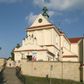 Zdjęcie nr 1: Kościół murowany, orientowany, jednonawowy, z transeptem, prezbiterium z obejściem i przybudówkami. Od zachodu kruchta, od północy kwadratowa kaplica, od południa kolejna przybudówka. 
Prezbiterium zamknięte półokrągło, z obejściem przeprutym do niego arkadami wspartymi na filarach. Ściany nawy i prezbiterium gładkie, przekryte sklepieniem kolebkowym z lunetami, w których mieszczą się okna. Transept i przecięcie naw sklepione krzyżowo. Na ścianach polichromia figuralna ze scenami z Nowego Testamentu, w partii sklepienia drobne, złote gwiazdki. Od zachodu chór zatopiony w występującym asymetrycznie murze, z tralkową balustradą. W prezbiterium siedem okien w kształcie stojącego prostokąta zamkniętego łukiem pełnym wypełnionych witrażami, w nawie sześć okien, w ramionach transeptu po jednym, czterodzielnym, wypełnionym witrażem, na wysokości chóru po dwa z każdej strony. Główne wejście od zachodu przez kruchtę. Fasada poprzedzona przedsionkiem o podziałach ramowych, z prostokątnym wejściem na osi, flankowanym parą pilastrów i prostokątnymi płycinami. Kondygnację wieńczy pełne belkowanie z wysuniętym gzymsem podtrzymującym daszek i trójkątny, schodkowy szczyt zakończony postumentami. Na centralnym krzyż, na sąsiadujących figury dzieci z rogami obfitości, a na zewnętrznych wazony płomieniste; szczyt ujmują postumenty z kulami. Fasada dwukondygnacyjna ze szczytem. Kondygnacja trójosiowa, rozdzielona pilastrami, o polach wypełnionych blendami w kształcie stojących prostokątów zamkniętych łukiem pełnym; szczyt trójkątny, z tarczą zegarową pośrodku. Budynek kościoła o wyraźnych podziałach na bryły składowe, ściany gładkie, przeprute oknami, z gzymsami pod krawędziami dachu. 
Nad nawą główną, na kalenicy, wieżyczka na sygnaturkę z latarnią i baniastym hełmem, druga na skrzyżowaniu naw, z latarnią i  hełmem zakończonym krzyżem. Dach nad nawą główną i przedsionkiem dwuspadowy, nad ramionami transeptu trójspadowym,nad prezbiterium zakończony wielobocznie, na przybudówkach dachy pulpitowe, dwuspadowe i wielospadowe. Dachy kryte dachówką ceramiczną, wieżyczki blachą. 
Najciekawszymi zabytkami kościoła są ołtarz główny z około 1700 roku z nastawą utworzoną z wici winnej latorośli, manierystyczny ołtarz boczny oraz siedemnastowieczna chrzcielnica z warsztatu Santi Gucciego. 
