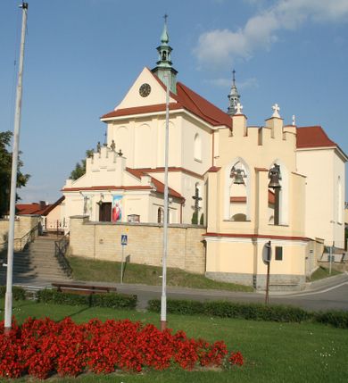 Zdjęcie nr 2: Kościół murowany, orientowany, jednonawowy, z transeptem, prezbiterium z obejściem i przybudówkami. Od zachodu kruchta, od północy kwadratowa kaplica, od południa kolejna przybudówka. 
Prezbiterium zamknięte półokrągło, z obejściem przeprutym do niego arkadami wspartymi na filarach. Ściany nawy i prezbiterium gładkie, przekryte sklepieniem kolebkowym z lunetami, w których mieszczą się okna. Transept i przecięcie naw sklepione krzyżowo. Na ścianach polichromia figuralna ze scenami z Nowego Testamentu, w partii sklepienia drobne, złote gwiazdki. Od zachodu chór zatopiony w występującym asymetrycznie murze, z tralkową balustradą. W prezbiterium siedem okien w kształcie stojącego prostokąta zamkniętego łukiem pełnym wypełnionych witrażami, w nawie sześć okien, w ramionach transeptu po jednym, czterodzielnym, wypełnionym witrażem, na wysokości chóru po dwa z każdej strony. Główne wejście od zachodu przez kruchtę. Fasada poprzedzona przedsionkiem o podziałach ramowych, z prostokątnym wejściem na osi, flankowanym parą pilastrów i prostokątnymi płycinami. Kondygnację wieńczy pełne belkowanie z wysuniętym gzymsem podtrzymującym daszek i trójkątny, schodkowy szczyt zakończony postumentami. Na centralnym krzyż, na sąsiadujących figury dzieci z rogami obfitości, a na zewnętrznych wazony płomieniste; szczyt ujmują postumenty z kulami. Fasada dwukondygnacyjna ze szczytem. Kondygnacja trójosiowa, rozdzielona pilastrami, o polach wypełnionych blendami w kształcie stojących prostokątów zamkniętych łukiem pełnym; szczyt trójkątny, z tarczą zegarową pośrodku. Budynek kościoła o wyraźnych podziałach na bryły składowe, ściany gładkie, przeprute oknami, z gzymsami pod krawędziami dachu. 
Nad nawą główną, na kalenicy, wieżyczka na sygnaturkę z latarnią i baniastym hełmem, druga na skrzyżowaniu naw, z latarnią i  hełmem zakończonym krzyżem. Dach nad nawą główną i przedsionkiem dwuspadowy, nad ramionami transeptu trójspadowym,nad prezbiterium zakończony wielobocznie, na przybudówkach dachy pulpitowe, dwuspadowe i wielospadowe. Dachy kryte dachówką ceramiczną, wieżyczki blachą. 
Najciekawszymi zabytkami kościoła są ołtarz główny z około 1700 roku z nastawą utworzoną z wici winnej latorośli, manierystyczny ołtarz boczny oraz siedemnastowieczna chrzcielnica z warsztatu Santi Gucciego. 
