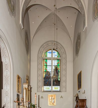 Zdjęcie nr 147: Kościół murowany, orientowany, jednonawowy, z transeptem, prezbiterium z obejściem i przybudówkami. Od zachodu kruchta, od północy kwadratowa kaplica, od południa kolejna przybudówka. 
Prezbiterium zamknięte półokrągło, z obejściem przeprutym do niego arkadami wspartymi na filarach. Ściany nawy i prezbiterium gładkie, przekryte sklepieniem kolebkowym z lunetami, w których mieszczą się okna. Transept i przecięcie naw sklepione krzyżowo. Na ścianach polichromia figuralna ze scenami z Nowego Testamentu, w partii sklepienia drobne, złote gwiazdki. Od zachodu chór zatopiony w występującym asymetrycznie murze, z tralkową balustradą. W prezbiterium siedem okien w kształcie stojącego prostokąta zamkniętego łukiem pełnym wypełnionych witrażami, w nawie sześć okien, w ramionach transeptu po jednym, czterodzielnym, wypełnionym witrażem, na wysokości chóru po dwa z każdej strony. Główne wejście od zachodu przez kruchtę. Fasada poprzedzona przedsionkiem o podziałach ramowych, z prostokątnym wejściem na osi, flankowanym parą pilastrów i prostokątnymi płycinami. Kondygnację wieńczy pełne belkowanie z wysuniętym gzymsem podtrzymującym daszek i trójkątny, schodkowy szczyt zakończony postumentami. Na centralnym krzyż, na sąsiadujących figury dzieci z rogami obfitości, a na zewnętrznych wazony płomieniste; szczyt ujmują postumenty z kulami. Fasada dwukondygnacyjna ze szczytem. Kondygnacja trójosiowa, rozdzielona pilastrami, o polach wypełnionych blendami w kształcie stojących prostokątów zamkniętych łukiem pełnym; szczyt trójkątny, z tarczą zegarową pośrodku. Budynek kościoła o wyraźnych podziałach na bryły składowe, ściany gładkie, przeprute oknami, z gzymsami pod krawędziami dachu. 
Nad nawą główną, na kalenicy, wieżyczka na sygnaturkę z latarnią i baniastym hełmem, druga na skrzyżowaniu naw, z latarnią i  hełmem zakończonym krzyżem. Dach nad nawą główną i przedsionkiem dwuspadowy, nad ramionami transeptu trójspadowym,nad prezbiterium zakończony wielobocznie, na przybudówkach dachy pulpitowe, dwuspadowe i wielospadowe. Dachy kryte dachówką ceramiczną, wieżyczki blachą. 
Najciekawszymi zabytkami kościoła są ołtarz główny z około 1700 roku z nastawą utworzoną z wici winnej latorośli, manierystyczny ołtarz boczny oraz siedemnastowieczna chrzcielnica z warsztatu Santi Gucciego. 
