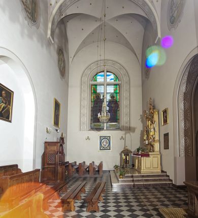 Zdjęcie nr 143: Kościół murowany, orientowany, jednonawowy, z transeptem, prezbiterium z obejściem i przybudówkami. Od zachodu kruchta, od północy kwadratowa kaplica, od południa kolejna przybudówka. 
Prezbiterium zamknięte półokrągło, z obejściem przeprutym do niego arkadami wspartymi na filarach. Ściany nawy i prezbiterium gładkie, przekryte sklepieniem kolebkowym z lunetami, w których mieszczą się okna. Transept i przecięcie naw sklepione krzyżowo. Na ścianach polichromia figuralna ze scenami z Nowego Testamentu, w partii sklepienia drobne, złote gwiazdki. Od zachodu chór zatopiony w występującym asymetrycznie murze, z tralkową balustradą. W prezbiterium siedem okien w kształcie stojącego prostokąta zamkniętego łukiem pełnym wypełnionych witrażami, w nawie sześć okien, w ramionach transeptu po jednym, czterodzielnym, wypełnionym witrażem, na wysokości chóru po dwa z każdej strony. Główne wejście od zachodu przez kruchtę. Fasada poprzedzona przedsionkiem o podziałach ramowych, z prostokątnym wejściem na osi, flankowanym parą pilastrów i prostokątnymi płycinami. Kondygnację wieńczy pełne belkowanie z wysuniętym gzymsem podtrzymującym daszek i trójkątny, schodkowy szczyt zakończony postumentami. Na centralnym krzyż, na sąsiadujących figury dzieci z rogami obfitości, a na zewnętrznych wazony płomieniste; szczyt ujmują postumenty z kulami. Fasada dwukondygnacyjna ze szczytem. Kondygnacja trójosiowa, rozdzielona pilastrami, o polach wypełnionych blendami w kształcie stojących prostokątów zamkniętych łukiem pełnym; szczyt trójkątny, z tarczą zegarową pośrodku. Budynek kościoła o wyraźnych podziałach na bryły składowe, ściany gładkie, przeprute oknami, z gzymsami pod krawędziami dachu. 
Nad nawą główną, na kalenicy, wieżyczka na sygnaturkę z latarnią i baniastym hełmem, druga na skrzyżowaniu naw, z latarnią i  hełmem zakończonym krzyżem. Dach nad nawą główną i przedsionkiem dwuspadowy, nad ramionami transeptu trójspadowym,nad prezbiterium zakończony wielobocznie, na przybudówkach dachy pulpitowe, dwuspadowe i wielospadowe. Dachy kryte dachówką ceramiczną, wieżyczki blachą. 
Najciekawszymi zabytkami kościoła są ołtarz główny z około 1700 roku z nastawą utworzoną z wici winnej latorośli, manierystyczny ołtarz boczny oraz siedemnastowieczna chrzcielnica z warsztatu Santi Gucciego. 
