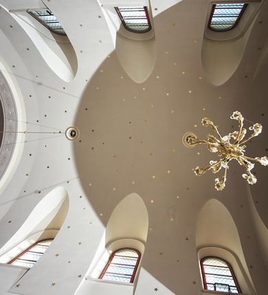 Zdjęcie nr 140: Kościół murowany, orientowany, jednonawowy, z transeptem, prezbiterium z obejściem i przybudówkami. Od zachodu kruchta, od północy kwadratowa kaplica, od południa kolejna przybudówka. 
Prezbiterium zamknięte półokrągło, z obejściem przeprutym do niego arkadami wspartymi na filarach. Ściany nawy i prezbiterium gładkie, przekryte sklepieniem kolebkowym z lunetami, w których mieszczą się okna. Transept i przecięcie naw sklepione krzyżowo. Na ścianach polichromia figuralna ze scenami z Nowego Testamentu, w partii sklepienia drobne, złote gwiazdki. Od zachodu chór zatopiony w występującym asymetrycznie murze, z tralkową balustradą. W prezbiterium siedem okien w kształcie stojącego prostokąta zamkniętego łukiem pełnym wypełnionych witrażami, w nawie sześć okien, w ramionach transeptu po jednym, czterodzielnym, wypełnionym witrażem, na wysokości chóru po dwa z każdej strony. Główne wejście od zachodu przez kruchtę. Fasada poprzedzona przedsionkiem o podziałach ramowych, z prostokątnym wejściem na osi, flankowanym parą pilastrów i prostokątnymi płycinami. Kondygnację wieńczy pełne belkowanie z wysuniętym gzymsem podtrzymującym daszek i trójkątny, schodkowy szczyt zakończony postumentami. Na centralnym krzyż, na sąsiadujących figury dzieci z rogami obfitości, a na zewnętrznych wazony płomieniste; szczyt ujmują postumenty z kulami. Fasada dwukondygnacyjna ze szczytem. Kondygnacja trójosiowa, rozdzielona pilastrami, o polach wypełnionych blendami w kształcie stojących prostokątów zamkniętych łukiem pełnym; szczyt trójkątny, z tarczą zegarową pośrodku. Budynek kościoła o wyraźnych podziałach na bryły składowe, ściany gładkie, przeprute oknami, z gzymsami pod krawędziami dachu. 
Nad nawą główną, na kalenicy, wieżyczka na sygnaturkę z latarnią i baniastym hełmem, druga na skrzyżowaniu naw, z latarnią i  hełmem zakończonym krzyżem. Dach nad nawą główną i przedsionkiem dwuspadowy, nad ramionami transeptu trójspadowym,nad prezbiterium zakończony wielobocznie, na przybudówkach dachy pulpitowe, dwuspadowe i wielospadowe. Dachy kryte dachówką ceramiczną, wieżyczki blachą. 
Najciekawszymi zabytkami kościoła są ołtarz główny z około 1700 roku z nastawą utworzoną z wici winnej latorośli, manierystyczny ołtarz boczny oraz siedemnastowieczna chrzcielnica z warsztatu Santi Gucciego. 
