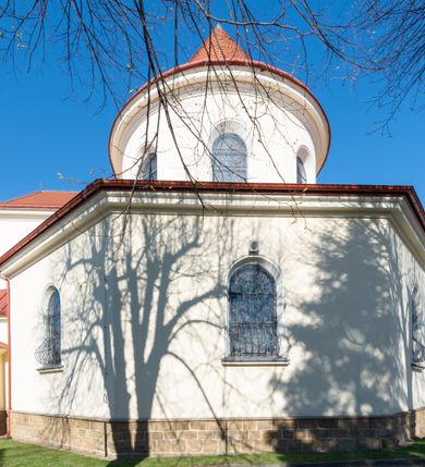 Zdjęcie nr 15: Kościół murowany, orientowany, jednonawowy, z transeptem, prezbiterium z obejściem i przybudówkami. Od zachodu kruchta, od północy kwadratowa kaplica, od południa kolejna przybudówka. 
Prezbiterium zamknięte półokrągło, z obejściem przeprutym do niego arkadami wspartymi na filarach. Ściany nawy i prezbiterium gładkie, przekryte sklepieniem kolebkowym z lunetami, w których mieszczą się okna. Transept i przecięcie naw sklepione krzyżowo. Na ścianach polichromia figuralna ze scenami z Nowego Testamentu, w partii sklepienia drobne, złote gwiazdki. Od zachodu chór zatopiony w występującym asymetrycznie murze, z tralkową balustradą. W prezbiterium siedem okien w kształcie stojącego prostokąta zamkniętego łukiem pełnym wypełnionych witrażami, w nawie sześć okien, w ramionach transeptu po jednym, czterodzielnym, wypełnionym witrażem, na wysokości chóru po dwa z każdej strony. Główne wejście od zachodu przez kruchtę. Fasada poprzedzona przedsionkiem o podziałach ramowych, z prostokątnym wejściem na osi, flankowanym parą pilastrów i prostokątnymi płycinami. Kondygnację wieńczy pełne belkowanie z wysuniętym gzymsem podtrzymującym daszek i trójkątny, schodkowy szczyt zakończony postumentami. Na centralnym krzyż, na sąsiadujących figury dzieci z rogami obfitości, a na zewnętrznych wazony płomieniste; szczyt ujmują postumenty z kulami. Fasada dwukondygnacyjna ze szczytem. Kondygnacja trójosiowa, rozdzielona pilastrami, o polach wypełnionych blendami w kształcie stojących prostokątów zamkniętych łukiem pełnym; szczyt trójkątny, z tarczą zegarową pośrodku. Budynek kościoła o wyraźnych podziałach na bryły składowe, ściany gładkie, przeprute oknami, z gzymsami pod krawędziami dachu. 
Nad nawą główną, na kalenicy, wieżyczka na sygnaturkę z latarnią i baniastym hełmem, druga na skrzyżowaniu naw, z latarnią i  hełmem zakończonym krzyżem. Dach nad nawą główną i przedsionkiem dwuspadowy, nad ramionami transeptu trójspadowym,nad prezbiterium zakończony wielobocznie, na przybudówkach dachy pulpitowe, dwuspadowe i wielospadowe. Dachy kryte dachówką ceramiczną, wieżyczki blachą. 
Najciekawszymi zabytkami kościoła są ołtarz główny z około 1700 roku z nastawą utworzoną z wici winnej latorośli, manierystyczny ołtarz boczny oraz siedemnastowieczna chrzcielnica z warsztatu Santi Gucciego. 
