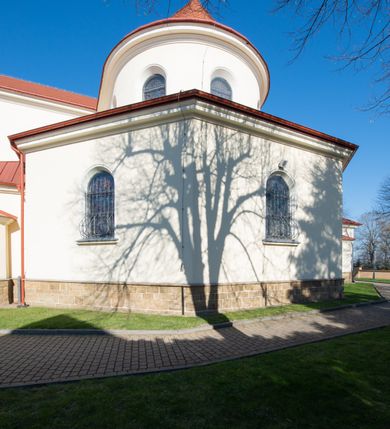 Zdjęcie nr 17: Kościół murowany, orientowany, jednonawowy, z transeptem, prezbiterium z obejściem i przybudówkami. Od zachodu kruchta, od północy kwadratowa kaplica, od południa kolejna przybudówka. 
Prezbiterium zamknięte półokrągło, z obejściem przeprutym do niego arkadami wspartymi na filarach. Ściany nawy i prezbiterium gładkie, przekryte sklepieniem kolebkowym z lunetami, w których mieszczą się okna. Transept i przecięcie naw sklepione krzyżowo. Na ścianach polichromia figuralna ze scenami z Nowego Testamentu, w partii sklepienia drobne, złote gwiazdki. Od zachodu chór zatopiony w występującym asymetrycznie murze, z tralkową balustradą. W prezbiterium siedem okien w kształcie stojącego prostokąta zamkniętego łukiem pełnym wypełnionych witrażami, w nawie sześć okien, w ramionach transeptu po jednym, czterodzielnym, wypełnionym witrażem, na wysokości chóru po dwa z każdej strony. Główne wejście od zachodu przez kruchtę. Fasada poprzedzona przedsionkiem o podziałach ramowych, z prostokątnym wejściem na osi, flankowanym parą pilastrów i prostokątnymi płycinami. Kondygnację wieńczy pełne belkowanie z wysuniętym gzymsem podtrzymującym daszek i trójkątny, schodkowy szczyt zakończony postumentami. Na centralnym krzyż, na sąsiadujących figury dzieci z rogami obfitości, a na zewnętrznych wazony płomieniste; szczyt ujmują postumenty z kulami. Fasada dwukondygnacyjna ze szczytem. Kondygnacja trójosiowa, rozdzielona pilastrami, o polach wypełnionych blendami w kształcie stojących prostokątów zamkniętych łukiem pełnym; szczyt trójkątny, z tarczą zegarową pośrodku. Budynek kościoła o wyraźnych podziałach na bryły składowe, ściany gładkie, przeprute oknami, z gzymsami pod krawędziami dachu. 
Nad nawą główną, na kalenicy, wieżyczka na sygnaturkę z latarnią i baniastym hełmem, druga na skrzyżowaniu naw, z latarnią i  hełmem zakończonym krzyżem. Dach nad nawą główną i przedsionkiem dwuspadowy, nad ramionami transeptu trójspadowym,nad prezbiterium zakończony wielobocznie, na przybudówkach dachy pulpitowe, dwuspadowe i wielospadowe. Dachy kryte dachówką ceramiczną, wieżyczki blachą. 
Najciekawszymi zabytkami kościoła są ołtarz główny z około 1700 roku z nastawą utworzoną z wici winnej latorośli, manierystyczny ołtarz boczny oraz siedemnastowieczna chrzcielnica z warsztatu Santi Gucciego. 
