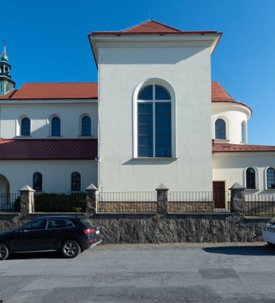 Zdjęcie nr 26: Kościół murowany, orientowany, jednonawowy, z transeptem, prezbiterium z obejściem i przybudówkami. Od zachodu kruchta, od północy kwadratowa kaplica, od południa kolejna przybudówka. 
Prezbiterium zamknięte półokrągło, z obejściem przeprutym do niego arkadami wspartymi na filarach. Ściany nawy i prezbiterium gładkie, przekryte sklepieniem kolebkowym z lunetami, w których mieszczą się okna. Transept i przecięcie naw sklepione krzyżowo. Na ścianach polichromia figuralna ze scenami z Nowego Testamentu, w partii sklepienia drobne, złote gwiazdki. Od zachodu chór zatopiony w występującym asymetrycznie murze, z tralkową balustradą. W prezbiterium siedem okien w kształcie stojącego prostokąta zamkniętego łukiem pełnym wypełnionych witrażami, w nawie sześć okien, w ramionach transeptu po jednym, czterodzielnym, wypełnionym witrażem, na wysokości chóru po dwa z każdej strony. Główne wejście od zachodu przez kruchtę. Fasada poprzedzona przedsionkiem o podziałach ramowych, z prostokątnym wejściem na osi, flankowanym parą pilastrów i prostokątnymi płycinami. Kondygnację wieńczy pełne belkowanie z wysuniętym gzymsem podtrzymującym daszek i trójkątny, schodkowy szczyt zakończony postumentami. Na centralnym krzyż, na sąsiadujących figury dzieci z rogami obfitości, a na zewnętrznych wazony płomieniste; szczyt ujmują postumenty z kulami. Fasada dwukondygnacyjna ze szczytem. Kondygnacja trójosiowa, rozdzielona pilastrami, o polach wypełnionych blendami w kształcie stojących prostokątów zamkniętych łukiem pełnym; szczyt trójkątny, z tarczą zegarową pośrodku. Budynek kościoła o wyraźnych podziałach na bryły składowe, ściany gładkie, przeprute oknami, z gzymsami pod krawędziami dachu. 
Nad nawą główną, na kalenicy, wieżyczka na sygnaturkę z latarnią i baniastym hełmem, druga na skrzyżowaniu naw, z latarnią i  hełmem zakończonym krzyżem. Dach nad nawą główną i przedsionkiem dwuspadowy, nad ramionami transeptu trójspadowym,nad prezbiterium zakończony wielobocznie, na przybudówkach dachy pulpitowe, dwuspadowe i wielospadowe. Dachy kryte dachówką ceramiczną, wieżyczki blachą. 
Najciekawszymi zabytkami kościoła są ołtarz główny z około 1700 roku z nastawą utworzoną z wici winnej latorośli, manierystyczny ołtarz boczny oraz siedemnastowieczna chrzcielnica z warsztatu Santi Gucciego. 
