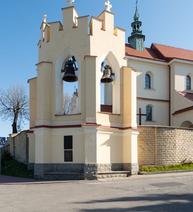 Zdjęcie nr 29: Kościół murowany, orientowany, jednonawowy, z transeptem, prezbiterium z obejściem i przybudówkami. Od zachodu kruchta, od północy kwadratowa kaplica, od południa kolejna przybudówka. 
Prezbiterium zamknięte półokrągło, z obejściem przeprutym do niego arkadami wspartymi na filarach. Ściany nawy i prezbiterium gładkie, przekryte sklepieniem kolebkowym z lunetami, w których mieszczą się okna. Transept i przecięcie naw sklepione krzyżowo. Na ścianach polichromia figuralna ze scenami z Nowego Testamentu, w partii sklepienia drobne, złote gwiazdki. Od zachodu chór zatopiony w występującym asymetrycznie murze, z tralkową balustradą. W prezbiterium siedem okien w kształcie stojącego prostokąta zamkniętego łukiem pełnym wypełnionych witrażami, w nawie sześć okien, w ramionach transeptu po jednym, czterodzielnym, wypełnionym witrażem, na wysokości chóru po dwa z każdej strony. Główne wejście od zachodu przez kruchtę. Fasada poprzedzona przedsionkiem o podziałach ramowych, z prostokątnym wejściem na osi, flankowanym parą pilastrów i prostokątnymi płycinami. Kondygnację wieńczy pełne belkowanie z wysuniętym gzymsem podtrzymującym daszek i trójkątny, schodkowy szczyt zakończony postumentami. Na centralnym krzyż, na sąsiadujących figury dzieci z rogami obfitości, a na zewnętrznych wazony płomieniste; szczyt ujmują postumenty z kulami. Fasada dwukondygnacyjna ze szczytem. Kondygnacja trójosiowa, rozdzielona pilastrami, o polach wypełnionych blendami w kształcie stojących prostokątów zamkniętych łukiem pełnym; szczyt trójkątny, z tarczą zegarową pośrodku. Budynek kościoła o wyraźnych podziałach na bryły składowe, ściany gładkie, przeprute oknami, z gzymsami pod krawędziami dachu. 
Nad nawą główną, na kalenicy, wieżyczka na sygnaturkę z latarnią i baniastym hełmem, druga na skrzyżowaniu naw, z latarnią i  hełmem zakończonym krzyżem. Dach nad nawą główną i przedsionkiem dwuspadowy, nad ramionami transeptu trójspadowym,nad prezbiterium zakończony wielobocznie, na przybudówkach dachy pulpitowe, dwuspadowe i wielospadowe. Dachy kryte dachówką ceramiczną, wieżyczki blachą. 
Najciekawszymi zabytkami kościoła są ołtarz główny z około 1700 roku z nastawą utworzoną z wici winnej latorośli, manierystyczny ołtarz boczny oraz siedemnastowieczna chrzcielnica z warsztatu Santi Gucciego. 
