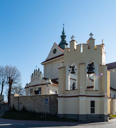 Zdjęcie nr 33: Kościół murowany, orientowany, jednonawowy, z transeptem, prezbiterium z obejściem i przybudówkami. Od zachodu kruchta, od północy kwadratowa kaplica, od południa kolejna przybudówka. 
Prezbiterium zamknięte półokrągło, z obejściem przeprutym do niego arkadami wspartymi na filarach. Ściany nawy i prezbiterium gładkie, przekryte sklepieniem kolebkowym z lunetami, w których mieszczą się okna. Transept i przecięcie naw sklepione krzyżowo. Na ścianach polichromia figuralna ze scenami z Nowego Testamentu, w partii sklepienia drobne, złote gwiazdki. Od zachodu chór zatopiony w występującym asymetrycznie murze, z tralkową balustradą. W prezbiterium siedem okien w kształcie stojącego prostokąta zamkniętego łukiem pełnym wypełnionych witrażami, w nawie sześć okien, w ramionach transeptu po jednym, czterodzielnym, wypełnionym witrażem, na wysokości chóru po dwa z każdej strony. Główne wejście od zachodu przez kruchtę. Fasada poprzedzona przedsionkiem o podziałach ramowych, z prostokątnym wejściem na osi, flankowanym parą pilastrów i prostokątnymi płycinami. Kondygnację wieńczy pełne belkowanie z wysuniętym gzymsem podtrzymującym daszek i trójkątny, schodkowy szczyt zakończony postumentami. Na centralnym krzyż, na sąsiadujących figury dzieci z rogami obfitości, a na zewnętrznych wazony płomieniste; szczyt ujmują postumenty z kulami. Fasada dwukondygnacyjna ze szczytem. Kondygnacja trójosiowa, rozdzielona pilastrami, o polach wypełnionych blendami w kształcie stojących prostokątów zamkniętych łukiem pełnym; szczyt trójkątny, z tarczą zegarową pośrodku. Budynek kościoła o wyraźnych podziałach na bryły składowe, ściany gładkie, przeprute oknami, z gzymsami pod krawędziami dachu. 
Nad nawą główną, na kalenicy, wieżyczka na sygnaturkę z latarnią i baniastym hełmem, druga na skrzyżowaniu naw, z latarnią i  hełmem zakończonym krzyżem. Dach nad nawą główną i przedsionkiem dwuspadowy, nad ramionami transeptu trójspadowym,nad prezbiterium zakończony wielobocznie, na przybudówkach dachy pulpitowe, dwuspadowe i wielospadowe. Dachy kryte dachówką ceramiczną, wieżyczki blachą. 
Najciekawszymi zabytkami kościoła są ołtarz główny z około 1700 roku z nastawą utworzoną z wici winnej latorośli, manierystyczny ołtarz boczny oraz siedemnastowieczna chrzcielnica z warsztatu Santi Gucciego. 
