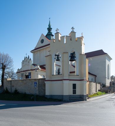 Zdjęcie nr 32: Kościół murowany, orientowany, jednonawowy, z transeptem, prezbiterium z obejściem i przybudówkami. Od zachodu kruchta, od północy kwadratowa kaplica, od południa kolejna przybudówka. 
Prezbiterium zamknięte półokrągło, z obejściem przeprutym do niego arkadami wspartymi na filarach. Ściany nawy i prezbiterium gładkie, przekryte sklepieniem kolebkowym z lunetami, w których mieszczą się okna. Transept i przecięcie naw sklepione krzyżowo. Na ścianach polichromia figuralna ze scenami z Nowego Testamentu, w partii sklepienia drobne, złote gwiazdki. Od zachodu chór zatopiony w występującym asymetrycznie murze, z tralkową balustradą. W prezbiterium siedem okien w kształcie stojącego prostokąta zamkniętego łukiem pełnym wypełnionych witrażami, w nawie sześć okien, w ramionach transeptu po jednym, czterodzielnym, wypełnionym witrażem, na wysokości chóru po dwa z każdej strony. Główne wejście od zachodu przez kruchtę. Fasada poprzedzona przedsionkiem o podziałach ramowych, z prostokątnym wejściem na osi, flankowanym parą pilastrów i prostokątnymi płycinami. Kondygnację wieńczy pełne belkowanie z wysuniętym gzymsem podtrzymującym daszek i trójkątny, schodkowy szczyt zakończony postumentami. Na centralnym krzyż, na sąsiadujących figury dzieci z rogami obfitości, a na zewnętrznych wazony płomieniste; szczyt ujmują postumenty z kulami. Fasada dwukondygnacyjna ze szczytem. Kondygnacja trójosiowa, rozdzielona pilastrami, o polach wypełnionych blendami w kształcie stojących prostokątów zamkniętych łukiem pełnym; szczyt trójkątny, z tarczą zegarową pośrodku. Budynek kościoła o wyraźnych podziałach na bryły składowe, ściany gładkie, przeprute oknami, z gzymsami pod krawędziami dachu. 
Nad nawą główną, na kalenicy, wieżyczka na sygnaturkę z latarnią i baniastym hełmem, druga na skrzyżowaniu naw, z latarnią i  hełmem zakończonym krzyżem. Dach nad nawą główną i przedsionkiem dwuspadowy, nad ramionami transeptu trójspadowym,nad prezbiterium zakończony wielobocznie, na przybudówkach dachy pulpitowe, dwuspadowe i wielospadowe. Dachy kryte dachówką ceramiczną, wieżyczki blachą. 
Najciekawszymi zabytkami kościoła są ołtarz główny z około 1700 roku z nastawą utworzoną z wici winnej latorośli, manierystyczny ołtarz boczny oraz siedemnastowieczna chrzcielnica z warsztatu Santi Gucciego. 
