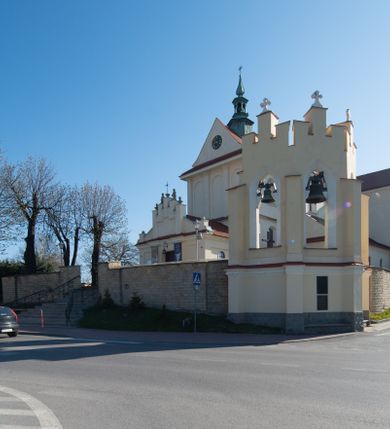 Zdjęcie nr 37: Kościół murowany, orientowany, jednonawowy, z transeptem, prezbiterium z obejściem i przybudówkami. Od zachodu kruchta, od północy kwadratowa kaplica, od południa kolejna przybudówka. 
Prezbiterium zamknięte półokrągło, z obejściem przeprutym do niego arkadami wspartymi na filarach. Ściany nawy i prezbiterium gładkie, przekryte sklepieniem kolebkowym z lunetami, w których mieszczą się okna. Transept i przecięcie naw sklepione krzyżowo. Na ścianach polichromia figuralna ze scenami z Nowego Testamentu, w partii sklepienia drobne, złote gwiazdki. Od zachodu chór zatopiony w występującym asymetrycznie murze, z tralkową balustradą. W prezbiterium siedem okien w kształcie stojącego prostokąta zamkniętego łukiem pełnym wypełnionych witrażami, w nawie sześć okien, w ramionach transeptu po jednym, czterodzielnym, wypełnionym witrażem, na wysokości chóru po dwa z każdej strony. Główne wejście od zachodu przez kruchtę. Fasada poprzedzona przedsionkiem o podziałach ramowych, z prostokątnym wejściem na osi, flankowanym parą pilastrów i prostokątnymi płycinami. Kondygnację wieńczy pełne belkowanie z wysuniętym gzymsem podtrzymującym daszek i trójkątny, schodkowy szczyt zakończony postumentami. Na centralnym krzyż, na sąsiadujących figury dzieci z rogami obfitości, a na zewnętrznych wazony płomieniste; szczyt ujmują postumenty z kulami. Fasada dwukondygnacyjna ze szczytem. Kondygnacja trójosiowa, rozdzielona pilastrami, o polach wypełnionych blendami w kształcie stojących prostokątów zamkniętych łukiem pełnym; szczyt trójkątny, z tarczą zegarową pośrodku. Budynek kościoła o wyraźnych podziałach na bryły składowe, ściany gładkie, przeprute oknami, z gzymsami pod krawędziami dachu. 
Nad nawą główną, na kalenicy, wieżyczka na sygnaturkę z latarnią i baniastym hełmem, druga na skrzyżowaniu naw, z latarnią i  hełmem zakończonym krzyżem. Dach nad nawą główną i przedsionkiem dwuspadowy, nad ramionami transeptu trójspadowym,nad prezbiterium zakończony wielobocznie, na przybudówkach dachy pulpitowe, dwuspadowe i wielospadowe. Dachy kryte dachówką ceramiczną, wieżyczki blachą. 
Najciekawszymi zabytkami kościoła są ołtarz główny z około 1700 roku z nastawą utworzoną z wici winnej latorośli, manierystyczny ołtarz boczny oraz siedemnastowieczna chrzcielnica z warsztatu Santi Gucciego. 
