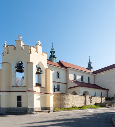 Zdjęcie nr 35: Kościół murowany, orientowany, jednonawowy, z transeptem, prezbiterium z obejściem i przybudówkami. Od zachodu kruchta, od północy kwadratowa kaplica, od południa kolejna przybudówka. 
Prezbiterium zamknięte półokrągło, z obejściem przeprutym do niego arkadami wspartymi na filarach. Ściany nawy i prezbiterium gładkie, przekryte sklepieniem kolebkowym z lunetami, w których mieszczą się okna. Transept i przecięcie naw sklepione krzyżowo. Na ścianach polichromia figuralna ze scenami z Nowego Testamentu, w partii sklepienia drobne, złote gwiazdki. Od zachodu chór zatopiony w występującym asymetrycznie murze, z tralkową balustradą. W prezbiterium siedem okien w kształcie stojącego prostokąta zamkniętego łukiem pełnym wypełnionych witrażami, w nawie sześć okien, w ramionach transeptu po jednym, czterodzielnym, wypełnionym witrażem, na wysokości chóru po dwa z każdej strony. Główne wejście od zachodu przez kruchtę. Fasada poprzedzona przedsionkiem o podziałach ramowych, z prostokątnym wejściem na osi, flankowanym parą pilastrów i prostokątnymi płycinami. Kondygnację wieńczy pełne belkowanie z wysuniętym gzymsem podtrzymującym daszek i trójkątny, schodkowy szczyt zakończony postumentami. Na centralnym krzyż, na sąsiadujących figury dzieci z rogami obfitości, a na zewnętrznych wazony płomieniste; szczyt ujmują postumenty z kulami. Fasada dwukondygnacyjna ze szczytem. Kondygnacja trójosiowa, rozdzielona pilastrami, o polach wypełnionych blendami w kształcie stojących prostokątów zamkniętych łukiem pełnym; szczyt trójkątny, z tarczą zegarową pośrodku. Budynek kościoła o wyraźnych podziałach na bryły składowe, ściany gładkie, przeprute oknami, z gzymsami pod krawędziami dachu. 
Nad nawą główną, na kalenicy, wieżyczka na sygnaturkę z latarnią i baniastym hełmem, druga na skrzyżowaniu naw, z latarnią i  hełmem zakończonym krzyżem. Dach nad nawą główną i przedsionkiem dwuspadowy, nad ramionami transeptu trójspadowym,nad prezbiterium zakończony wielobocznie, na przybudówkach dachy pulpitowe, dwuspadowe i wielospadowe. Dachy kryte dachówką ceramiczną, wieżyczki blachą. 
Najciekawszymi zabytkami kościoła są ołtarz główny z około 1700 roku z nastawą utworzoną z wici winnej latorośli, manierystyczny ołtarz boczny oraz siedemnastowieczna chrzcielnica z warsztatu Santi Gucciego. 
