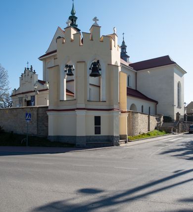 Zdjęcie nr 38: Kościół murowany, orientowany, jednonawowy, z transeptem, prezbiterium z obejściem i przybudówkami. Od zachodu kruchta, od północy kwadratowa kaplica, od południa kolejna przybudówka. 
Prezbiterium zamknięte półokrągło, z obejściem przeprutym do niego arkadami wspartymi na filarach. Ściany nawy i prezbiterium gładkie, przekryte sklepieniem kolebkowym z lunetami, w których mieszczą się okna. Transept i przecięcie naw sklepione krzyżowo. Na ścianach polichromia figuralna ze scenami z Nowego Testamentu, w partii sklepienia drobne, złote gwiazdki. Od zachodu chór zatopiony w występującym asymetrycznie murze, z tralkową balustradą. W prezbiterium siedem okien w kształcie stojącego prostokąta zamkniętego łukiem pełnym wypełnionych witrażami, w nawie sześć okien, w ramionach transeptu po jednym, czterodzielnym, wypełnionym witrażem, na wysokości chóru po dwa z każdej strony. Główne wejście od zachodu przez kruchtę. Fasada poprzedzona przedsionkiem o podziałach ramowych, z prostokątnym wejściem na osi, flankowanym parą pilastrów i prostokątnymi płycinami. Kondygnację wieńczy pełne belkowanie z wysuniętym gzymsem podtrzymującym daszek i trójkątny, schodkowy szczyt zakończony postumentami. Na centralnym krzyż, na sąsiadujących figury dzieci z rogami obfitości, a na zewnętrznych wazony płomieniste; szczyt ujmują postumenty z kulami. Fasada dwukondygnacyjna ze szczytem. Kondygnacja trójosiowa, rozdzielona pilastrami, o polach wypełnionych blendami w kształcie stojących prostokątów zamkniętych łukiem pełnym; szczyt trójkątny, z tarczą zegarową pośrodku. Budynek kościoła o wyraźnych podziałach na bryły składowe, ściany gładkie, przeprute oknami, z gzymsami pod krawędziami dachu. 
Nad nawą główną, na kalenicy, wieżyczka na sygnaturkę z latarnią i baniastym hełmem, druga na skrzyżowaniu naw, z latarnią i  hełmem zakończonym krzyżem. Dach nad nawą główną i przedsionkiem dwuspadowy, nad ramionami transeptu trójspadowym,nad prezbiterium zakończony wielobocznie, na przybudówkach dachy pulpitowe, dwuspadowe i wielospadowe. Dachy kryte dachówką ceramiczną, wieżyczki blachą. 
Najciekawszymi zabytkami kościoła są ołtarz główny z około 1700 roku z nastawą utworzoną z wici winnej latorośli, manierystyczny ołtarz boczny oraz siedemnastowieczna chrzcielnica z warsztatu Santi Gucciego. 
