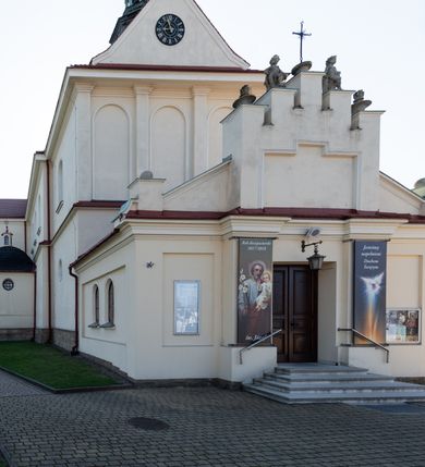 Zdjęcie nr 42: Kościół murowany, orientowany, jednonawowy, z transeptem, prezbiterium z obejściem i przybudówkami. Od zachodu kruchta, od północy kwadratowa kaplica, od południa kolejna przybudówka. 
Prezbiterium zamknięte półokrągło, z obejściem przeprutym do niego arkadami wspartymi na filarach. Ściany nawy i prezbiterium gładkie, przekryte sklepieniem kolebkowym z lunetami, w których mieszczą się okna. Transept i przecięcie naw sklepione krzyżowo. Na ścianach polichromia figuralna ze scenami z Nowego Testamentu, w partii sklepienia drobne, złote gwiazdki. Od zachodu chór zatopiony w występującym asymetrycznie murze, z tralkową balustradą. W prezbiterium siedem okien w kształcie stojącego prostokąta zamkniętego łukiem pełnym wypełnionych witrażami, w nawie sześć okien, w ramionach transeptu po jednym, czterodzielnym, wypełnionym witrażem, na wysokości chóru po dwa z każdej strony. Główne wejście od zachodu przez kruchtę. Fasada poprzedzona przedsionkiem o podziałach ramowych, z prostokątnym wejściem na osi, flankowanym parą pilastrów i prostokątnymi płycinami. Kondygnację wieńczy pełne belkowanie z wysuniętym gzymsem podtrzymującym daszek i trójkątny, schodkowy szczyt zakończony postumentami. Na centralnym krzyż, na sąsiadujących figury dzieci z rogami obfitości, a na zewnętrznych wazony płomieniste; szczyt ujmują postumenty z kulami. Fasada dwukondygnacyjna ze szczytem. Kondygnacja trójosiowa, rozdzielona pilastrami, o polach wypełnionych blendami w kształcie stojących prostokątów zamkniętych łukiem pełnym; szczyt trójkątny, z tarczą zegarową pośrodku. Budynek kościoła o wyraźnych podziałach na bryły składowe, ściany gładkie, przeprute oknami, z gzymsami pod krawędziami dachu. 
Nad nawą główną, na kalenicy, wieżyczka na sygnaturkę z latarnią i baniastym hełmem, druga na skrzyżowaniu naw, z latarnią i  hełmem zakończonym krzyżem. Dach nad nawą główną i przedsionkiem dwuspadowy, nad ramionami transeptu trójspadowym,nad prezbiterium zakończony wielobocznie, na przybudówkach dachy pulpitowe, dwuspadowe i wielospadowe. Dachy kryte dachówką ceramiczną, wieżyczki blachą. 
Najciekawszymi zabytkami kościoła są ołtarz główny z około 1700 roku z nastawą utworzoną z wici winnej latorośli, manierystyczny ołtarz boczny oraz siedemnastowieczna chrzcielnica z warsztatu Santi Gucciego. 
