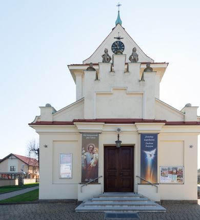 Zdjęcie nr 43: Kościół murowany, orientowany, jednonawowy, z transeptem, prezbiterium z obejściem i przybudówkami. Od zachodu kruchta, od północy kwadratowa kaplica, od południa kolejna przybudówka. 
Prezbiterium zamknięte półokrągło, z obejściem przeprutym do niego arkadami wspartymi na filarach. Ściany nawy i prezbiterium gładkie, przekryte sklepieniem kolebkowym z lunetami, w których mieszczą się okna. Transept i przecięcie naw sklepione krzyżowo. Na ścianach polichromia figuralna ze scenami z Nowego Testamentu, w partii sklepienia drobne, złote gwiazdki. Od zachodu chór zatopiony w występującym asymetrycznie murze, z tralkową balustradą. W prezbiterium siedem okien w kształcie stojącego prostokąta zamkniętego łukiem pełnym wypełnionych witrażami, w nawie sześć okien, w ramionach transeptu po jednym, czterodzielnym, wypełnionym witrażem, na wysokości chóru po dwa z każdej strony. Główne wejście od zachodu przez kruchtę. Fasada poprzedzona przedsionkiem o podziałach ramowych, z prostokątnym wejściem na osi, flankowanym parą pilastrów i prostokątnymi płycinami. Kondygnację wieńczy pełne belkowanie z wysuniętym gzymsem podtrzymującym daszek i trójkątny, schodkowy szczyt zakończony postumentami. Na centralnym krzyż, na sąsiadujących figury dzieci z rogami obfitości, a na zewnętrznych wazony płomieniste; szczyt ujmują postumenty z kulami. Fasada dwukondygnacyjna ze szczytem. Kondygnacja trójosiowa, rozdzielona pilastrami, o polach wypełnionych blendami w kształcie stojących prostokątów zamkniętych łukiem pełnym; szczyt trójkątny, z tarczą zegarową pośrodku. Budynek kościoła o wyraźnych podziałach na bryły składowe, ściany gładkie, przeprute oknami, z gzymsami pod krawędziami dachu. 
Nad nawą główną, na kalenicy, wieżyczka na sygnaturkę z latarnią i baniastym hełmem, druga na skrzyżowaniu naw, z latarnią i  hełmem zakończonym krzyżem. Dach nad nawą główną i przedsionkiem dwuspadowy, nad ramionami transeptu trójspadowym,nad prezbiterium zakończony wielobocznie, na przybudówkach dachy pulpitowe, dwuspadowe i wielospadowe. Dachy kryte dachówką ceramiczną, wieżyczki blachą. 
Najciekawszymi zabytkami kościoła są ołtarz główny z około 1700 roku z nastawą utworzoną z wici winnej latorośli, manierystyczny ołtarz boczny oraz siedemnastowieczna chrzcielnica z warsztatu Santi Gucciego. 
