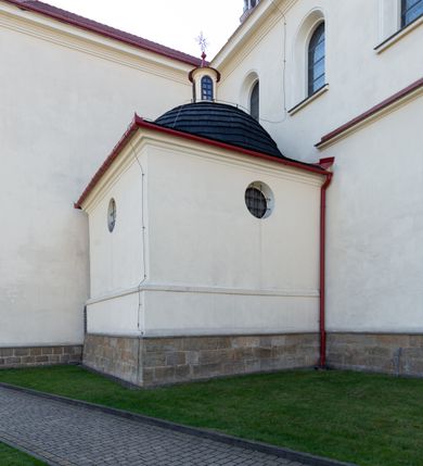 Zdjęcie nr 59: Kościół murowany, orientowany, jednonawowy, z transeptem, prezbiterium z obejściem i przybudówkami. Od zachodu kruchta, od północy kwadratowa kaplica, od południa kolejna przybudówka. 
Prezbiterium zamknięte półokrągło, z obejściem przeprutym do niego arkadami wspartymi na filarach. Ściany nawy i prezbiterium gładkie, przekryte sklepieniem kolebkowym z lunetami, w których mieszczą się okna. Transept i przecięcie naw sklepione krzyżowo. Na ścianach polichromia figuralna ze scenami z Nowego Testamentu, w partii sklepienia drobne, złote gwiazdki. Od zachodu chór zatopiony w występującym asymetrycznie murze, z tralkową balustradą. W prezbiterium siedem okien w kształcie stojącego prostokąta zamkniętego łukiem pełnym wypełnionych witrażami, w nawie sześć okien, w ramionach transeptu po jednym, czterodzielnym, wypełnionym witrażem, na wysokości chóru po dwa z każdej strony. Główne wejście od zachodu przez kruchtę. Fasada poprzedzona przedsionkiem o podziałach ramowych, z prostokątnym wejściem na osi, flankowanym parą pilastrów i prostokątnymi płycinami. Kondygnację wieńczy pełne belkowanie z wysuniętym gzymsem podtrzymującym daszek i trójkątny, schodkowy szczyt zakończony postumentami. Na centralnym krzyż, na sąsiadujących figury dzieci z rogami obfitości, a na zewnętrznych wazony płomieniste; szczyt ujmują postumenty z kulami. Fasada dwukondygnacyjna ze szczytem. Kondygnacja trójosiowa, rozdzielona pilastrami, o polach wypełnionych blendami w kształcie stojących prostokątów zamkniętych łukiem pełnym; szczyt trójkątny, z tarczą zegarową pośrodku. Budynek kościoła o wyraźnych podziałach na bryły składowe, ściany gładkie, przeprute oknami, z gzymsami pod krawędziami dachu. 
Nad nawą główną, na kalenicy, wieżyczka na sygnaturkę z latarnią i baniastym hełmem, druga na skrzyżowaniu naw, z latarnią i  hełmem zakończonym krzyżem. Dach nad nawą główną i przedsionkiem dwuspadowy, nad ramionami transeptu trójspadowym,nad prezbiterium zakończony wielobocznie, na przybudówkach dachy pulpitowe, dwuspadowe i wielospadowe. Dachy kryte dachówką ceramiczną, wieżyczki blachą. 
Najciekawszymi zabytkami kościoła są ołtarz główny z około 1700 roku z nastawą utworzoną z wici winnej latorośli, manierystyczny ołtarz boczny oraz siedemnastowieczna chrzcielnica z warsztatu Santi Gucciego. 
