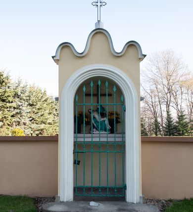 Zdjęcie nr 58: Kościół murowany, orientowany, jednonawowy, z transeptem, prezbiterium z obejściem i przybudówkami. Od zachodu kruchta, od północy kwadratowa kaplica, od południa kolejna przybudówka. 
Prezbiterium zamknięte półokrągło, z obejściem przeprutym do niego arkadami wspartymi na filarach. Ściany nawy i prezbiterium gładkie, przekryte sklepieniem kolebkowym z lunetami, w których mieszczą się okna. Transept i przecięcie naw sklepione krzyżowo. Na ścianach polichromia figuralna ze scenami z Nowego Testamentu, w partii sklepienia drobne, złote gwiazdki. Od zachodu chór zatopiony w występującym asymetrycznie murze, z tralkową balustradą. W prezbiterium siedem okien w kształcie stojącego prostokąta zamkniętego łukiem pełnym wypełnionych witrażami, w nawie sześć okien, w ramionach transeptu po jednym, czterodzielnym, wypełnionym witrażem, na wysokości chóru po dwa z każdej strony. Główne wejście od zachodu przez kruchtę. Fasada poprzedzona przedsionkiem o podziałach ramowych, z prostokątnym wejściem na osi, flankowanym parą pilastrów i prostokątnymi płycinami. Kondygnację wieńczy pełne belkowanie z wysuniętym gzymsem podtrzymującym daszek i trójkątny, schodkowy szczyt zakończony postumentami. Na centralnym krzyż, na sąsiadujących figury dzieci z rogami obfitości, a na zewnętrznych wazony płomieniste; szczyt ujmują postumenty z kulami. Fasada dwukondygnacyjna ze szczytem. Kondygnacja trójosiowa, rozdzielona pilastrami, o polach wypełnionych blendami w kształcie stojących prostokątów zamkniętych łukiem pełnym; szczyt trójkątny, z tarczą zegarową pośrodku. Budynek kościoła o wyraźnych podziałach na bryły składowe, ściany gładkie, przeprute oknami, z gzymsami pod krawędziami dachu. 
Nad nawą główną, na kalenicy, wieżyczka na sygnaturkę z latarnią i baniastym hełmem, druga na skrzyżowaniu naw, z latarnią i  hełmem zakończonym krzyżem. Dach nad nawą główną i przedsionkiem dwuspadowy, nad ramionami transeptu trójspadowym,nad prezbiterium zakończony wielobocznie, na przybudówkach dachy pulpitowe, dwuspadowe i wielospadowe. Dachy kryte dachówką ceramiczną, wieżyczki blachą. 
Najciekawszymi zabytkami kościoła są ołtarz główny z około 1700 roku z nastawą utworzoną z wici winnej latorośli, manierystyczny ołtarz boczny oraz siedemnastowieczna chrzcielnica z warsztatu Santi Gucciego. 
