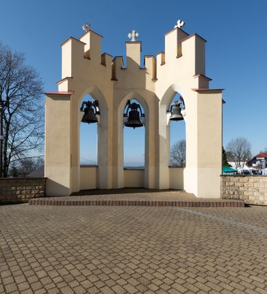 Zdjęcie nr 60: Kościół murowany, orientowany, jednonawowy, z transeptem, prezbiterium z obejściem i przybudówkami. Od zachodu kruchta, od północy kwadratowa kaplica, od południa kolejna przybudówka. 
Prezbiterium zamknięte półokrągło, z obejściem przeprutym do niego arkadami wspartymi na filarach. Ściany nawy i prezbiterium gładkie, przekryte sklepieniem kolebkowym z lunetami, w których mieszczą się okna. Transept i przecięcie naw sklepione krzyżowo. Na ścianach polichromia figuralna ze scenami z Nowego Testamentu, w partii sklepienia drobne, złote gwiazdki. Od zachodu chór zatopiony w występującym asymetrycznie murze, z tralkową balustradą. W prezbiterium siedem okien w kształcie stojącego prostokąta zamkniętego łukiem pełnym wypełnionych witrażami, w nawie sześć okien, w ramionach transeptu po jednym, czterodzielnym, wypełnionym witrażem, na wysokości chóru po dwa z każdej strony. Główne wejście od zachodu przez kruchtę. Fasada poprzedzona przedsionkiem o podziałach ramowych, z prostokątnym wejściem na osi, flankowanym parą pilastrów i prostokątnymi płycinami. Kondygnację wieńczy pełne belkowanie z wysuniętym gzymsem podtrzymującym daszek i trójkątny, schodkowy szczyt zakończony postumentami. Na centralnym krzyż, na sąsiadujących figury dzieci z rogami obfitości, a na zewnętrznych wazony płomieniste; szczyt ujmują postumenty z kulami. Fasada dwukondygnacyjna ze szczytem. Kondygnacja trójosiowa, rozdzielona pilastrami, o polach wypełnionych blendami w kształcie stojących prostokątów zamkniętych łukiem pełnym; szczyt trójkątny, z tarczą zegarową pośrodku. Budynek kościoła o wyraźnych podziałach na bryły składowe, ściany gładkie, przeprute oknami, z gzymsami pod krawędziami dachu. 
Nad nawą główną, na kalenicy, wieżyczka na sygnaturkę z latarnią i baniastym hełmem, druga na skrzyżowaniu naw, z latarnią i  hełmem zakończonym krzyżem. Dach nad nawą główną i przedsionkiem dwuspadowy, nad ramionami transeptu trójspadowym,nad prezbiterium zakończony wielobocznie, na przybudówkach dachy pulpitowe, dwuspadowe i wielospadowe. Dachy kryte dachówką ceramiczną, wieżyczki blachą. 
Najciekawszymi zabytkami kościoła są ołtarz główny z około 1700 roku z nastawą utworzoną z wici winnej latorośli, manierystyczny ołtarz boczny oraz siedemnastowieczna chrzcielnica z warsztatu Santi Gucciego. 
