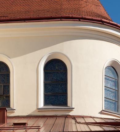 Zdjęcie nr 80: Kościół murowany, orientowany, jednonawowy, z transeptem, prezbiterium z obejściem i przybudówkami. Od zachodu kruchta, od północy kwadratowa kaplica, od południa kolejna przybudówka. 
Prezbiterium zamknięte półokrągło, z obejściem przeprutym do niego arkadami wspartymi na filarach. Ściany nawy i prezbiterium gładkie, przekryte sklepieniem kolebkowym z lunetami, w których mieszczą się okna. Transept i przecięcie naw sklepione krzyżowo. Na ścianach polichromia figuralna ze scenami z Nowego Testamentu, w partii sklepienia drobne, złote gwiazdki. Od zachodu chór zatopiony w występującym asymetrycznie murze, z tralkową balustradą. W prezbiterium siedem okien w kształcie stojącego prostokąta zamkniętego łukiem pełnym wypełnionych witrażami, w nawie sześć okien, w ramionach transeptu po jednym, czterodzielnym, wypełnionym witrażem, na wysokości chóru po dwa z każdej strony. Główne wejście od zachodu przez kruchtę. Fasada poprzedzona przedsionkiem o podziałach ramowych, z prostokątnym wejściem na osi, flankowanym parą pilastrów i prostokątnymi płycinami. Kondygnację wieńczy pełne belkowanie z wysuniętym gzymsem podtrzymującym daszek i trójkątny, schodkowy szczyt zakończony postumentami. Na centralnym krzyż, na sąsiadujących figury dzieci z rogami obfitości, a na zewnętrznych wazony płomieniste; szczyt ujmują postumenty z kulami. Fasada dwukondygnacyjna ze szczytem. Kondygnacja trójosiowa, rozdzielona pilastrami, o polach wypełnionych blendami w kształcie stojących prostokątów zamkniętych łukiem pełnym; szczyt trójkątny, z tarczą zegarową pośrodku. Budynek kościoła o wyraźnych podziałach na bryły składowe, ściany gładkie, przeprute oknami, z gzymsami pod krawędziami dachu. 
Nad nawą główną, na kalenicy, wieżyczka na sygnaturkę z latarnią i baniastym hełmem, druga na skrzyżowaniu naw, z latarnią i  hełmem zakończonym krzyżem. Dach nad nawą główną i przedsionkiem dwuspadowy, nad ramionami transeptu trójspadowym,nad prezbiterium zakończony wielobocznie, na przybudówkach dachy pulpitowe, dwuspadowe i wielospadowe. Dachy kryte dachówką ceramiczną, wieżyczki blachą. 
Najciekawszymi zabytkami kościoła są ołtarz główny z około 1700 roku z nastawą utworzoną z wici winnej latorośli, manierystyczny ołtarz boczny oraz siedemnastowieczna chrzcielnica z warsztatu Santi Gucciego. 
