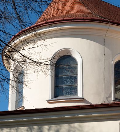 Zdjęcie nr 82: Kościół murowany, orientowany, jednonawowy, z transeptem, prezbiterium z obejściem i przybudówkami. Od zachodu kruchta, od północy kwadratowa kaplica, od południa kolejna przybudówka. 
Prezbiterium zamknięte półokrągło, z obejściem przeprutym do niego arkadami wspartymi na filarach. Ściany nawy i prezbiterium gładkie, przekryte sklepieniem kolebkowym z lunetami, w których mieszczą się okna. Transept i przecięcie naw sklepione krzyżowo. Na ścianach polichromia figuralna ze scenami z Nowego Testamentu, w partii sklepienia drobne, złote gwiazdki. Od zachodu chór zatopiony w występującym asymetrycznie murze, z tralkową balustradą. W prezbiterium siedem okien w kształcie stojącego prostokąta zamkniętego łukiem pełnym wypełnionych witrażami, w nawie sześć okien, w ramionach transeptu po jednym, czterodzielnym, wypełnionym witrażem, na wysokości chóru po dwa z każdej strony. Główne wejście od zachodu przez kruchtę. Fasada poprzedzona przedsionkiem o podziałach ramowych, z prostokątnym wejściem na osi, flankowanym parą pilastrów i prostokątnymi płycinami. Kondygnację wieńczy pełne belkowanie z wysuniętym gzymsem podtrzymującym daszek i trójkątny, schodkowy szczyt zakończony postumentami. Na centralnym krzyż, na sąsiadujących figury dzieci z rogami obfitości, a na zewnętrznych wazony płomieniste; szczyt ujmują postumenty z kulami. Fasada dwukondygnacyjna ze szczytem. Kondygnacja trójosiowa, rozdzielona pilastrami, o polach wypełnionych blendami w kształcie stojących prostokątów zamkniętych łukiem pełnym; szczyt trójkątny, z tarczą zegarową pośrodku. Budynek kościoła o wyraźnych podziałach na bryły składowe, ściany gładkie, przeprute oknami, z gzymsami pod krawędziami dachu. 
Nad nawą główną, na kalenicy, wieżyczka na sygnaturkę z latarnią i baniastym hełmem, druga na skrzyżowaniu naw, z latarnią i  hełmem zakończonym krzyżem. Dach nad nawą główną i przedsionkiem dwuspadowy, nad ramionami transeptu trójspadowym,nad prezbiterium zakończony wielobocznie, na przybudówkach dachy pulpitowe, dwuspadowe i wielospadowe. Dachy kryte dachówką ceramiczną, wieżyczki blachą. 
Najciekawszymi zabytkami kościoła są ołtarz główny z około 1700 roku z nastawą utworzoną z wici winnej latorośli, manierystyczny ołtarz boczny oraz siedemnastowieczna chrzcielnica z warsztatu Santi Gucciego. 
