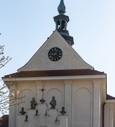 Zdjęcie nr 88: Kościół murowany, orientowany, jednonawowy, z transeptem, prezbiterium z obejściem i przybudówkami. Od zachodu kruchta, od północy kwadratowa kaplica, od południa kolejna przybudówka. 
Prezbiterium zamknięte półokrągło, z obejściem przeprutym do niego arkadami wspartymi na filarach. Ściany nawy i prezbiterium gładkie, przekryte sklepieniem kolebkowym z lunetami, w których mieszczą się okna. Transept i przecięcie naw sklepione krzyżowo. Na ścianach polichromia figuralna ze scenami z Nowego Testamentu, w partii sklepienia drobne, złote gwiazdki. Od zachodu chór zatopiony w występującym asymetrycznie murze, z tralkową balustradą. W prezbiterium siedem okien w kształcie stojącego prostokąta zamkniętego łukiem pełnym wypełnionych witrażami, w nawie sześć okien, w ramionach transeptu po jednym, czterodzielnym, wypełnionym witrażem, na wysokości chóru po dwa z każdej strony. Główne wejście od zachodu przez kruchtę. Fasada poprzedzona przedsionkiem o podziałach ramowych, z prostokątnym wejściem na osi, flankowanym parą pilastrów i prostokątnymi płycinami. Kondygnację wieńczy pełne belkowanie z wysuniętym gzymsem podtrzymującym daszek i trójkątny, schodkowy szczyt zakończony postumentami. Na centralnym krzyż, na sąsiadujących figury dzieci z rogami obfitości, a na zewnętrznych wazony płomieniste; szczyt ujmują postumenty z kulami. Fasada dwukondygnacyjna ze szczytem. Kondygnacja trójosiowa, rozdzielona pilastrami, o polach wypełnionych blendami w kształcie stojących prostokątów zamkniętych łukiem pełnym; szczyt trójkątny, z tarczą zegarową pośrodku. Budynek kościoła o wyraźnych podziałach na bryły składowe, ściany gładkie, przeprute oknami, z gzymsami pod krawędziami dachu. 
Nad nawą główną, na kalenicy, wieżyczka na sygnaturkę z latarnią i baniastym hełmem, druga na skrzyżowaniu naw, z latarnią i  hełmem zakończonym krzyżem. Dach nad nawą główną i przedsionkiem dwuspadowy, nad ramionami transeptu trójspadowym,nad prezbiterium zakończony wielobocznie, na przybudówkach dachy pulpitowe, dwuspadowe i wielospadowe. Dachy kryte dachówką ceramiczną, wieżyczki blachą. 
Najciekawszymi zabytkami kościoła są ołtarz główny z około 1700 roku z nastawą utworzoną z wici winnej latorośli, manierystyczny ołtarz boczny oraz siedemnastowieczna chrzcielnica z warsztatu Santi Gucciego. 
