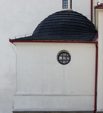 Zdjęcie nr 99: Kościół murowany, orientowany, jednonawowy, z transeptem, prezbiterium z obejściem i przybudówkami. Od zachodu kruchta, od północy kwadratowa kaplica, od południa kolejna przybudówka. 
Prezbiterium zamknięte półokrągło, z obejściem przeprutym do niego arkadami wspartymi na filarach. Ściany nawy i prezbiterium gładkie, przekryte sklepieniem kolebkowym z lunetami, w których mieszczą się okna. Transept i przecięcie naw sklepione krzyżowo. Na ścianach polichromia figuralna ze scenami z Nowego Testamentu, w partii sklepienia drobne, złote gwiazdki. Od zachodu chór zatopiony w występującym asymetrycznie murze, z tralkową balustradą. W prezbiterium siedem okien w kształcie stojącego prostokąta zamkniętego łukiem pełnym wypełnionych witrażami, w nawie sześć okien, w ramionach transeptu po jednym, czterodzielnym, wypełnionym witrażem, na wysokości chóru po dwa z każdej strony. Główne wejście od zachodu przez kruchtę. Fasada poprzedzona przedsionkiem o podziałach ramowych, z prostokątnym wejściem na osi, flankowanym parą pilastrów i prostokątnymi płycinami. Kondygnację wieńczy pełne belkowanie z wysuniętym gzymsem podtrzymującym daszek i trójkątny, schodkowy szczyt zakończony postumentami. Na centralnym krzyż, na sąsiadujących figury dzieci z rogami obfitości, a na zewnętrznych wazony płomieniste; szczyt ujmują postumenty z kulami. Fasada dwukondygnacyjna ze szczytem. Kondygnacja trójosiowa, rozdzielona pilastrami, o polach wypełnionych blendami w kształcie stojących prostokątów zamkniętych łukiem pełnym; szczyt trójkątny, z tarczą zegarową pośrodku. Budynek kościoła o wyraźnych podziałach na bryły składowe, ściany gładkie, przeprute oknami, z gzymsami pod krawędziami dachu. 
Nad nawą główną, na kalenicy, wieżyczka na sygnaturkę z latarnią i baniastym hełmem, druga na skrzyżowaniu naw, z latarnią i  hełmem zakończonym krzyżem. Dach nad nawą główną i przedsionkiem dwuspadowy, nad ramionami transeptu trójspadowym,nad prezbiterium zakończony wielobocznie, na przybudówkach dachy pulpitowe, dwuspadowe i wielospadowe. Dachy kryte dachówką ceramiczną, wieżyczki blachą. 
Najciekawszymi zabytkami kościoła są ołtarz główny z około 1700 roku z nastawą utworzoną z wici winnej latorośli, manierystyczny ołtarz boczny oraz siedemnastowieczna chrzcielnica z warsztatu Santi Gucciego. 
