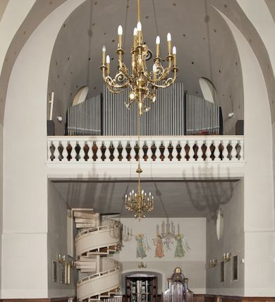 Zdjęcie nr 129: Kościół murowany, orientowany, jednonawowy, z transeptem, prezbiterium z obejściem i przybudówkami. Od zachodu kruchta, od północy kwadratowa kaplica, od południa kolejna przybudówka. 
Prezbiterium zamknięte półokrągło, z obejściem przeprutym do niego arkadami wspartymi na filarach. Ściany nawy i prezbiterium gładkie, przekryte sklepieniem kolebkowym z lunetami, w których mieszczą się okna. Transept i przecięcie naw sklepione krzyżowo. Na ścianach polichromia figuralna ze scenami z Nowego Testamentu, w partii sklepienia drobne, złote gwiazdki. Od zachodu chór zatopiony w występującym asymetrycznie murze, z tralkową balustradą. W prezbiterium siedem okien w kształcie stojącego prostokąta zamkniętego łukiem pełnym wypełnionych witrażami, w nawie sześć okien, w ramionach transeptu po jednym, czterodzielnym, wypełnionym witrażem, na wysokości chóru po dwa z każdej strony. Główne wejście od zachodu przez kruchtę. Fasada poprzedzona przedsionkiem o podziałach ramowych, z prostokątnym wejściem na osi, flankowanym parą pilastrów i prostokątnymi płycinami. Kondygnację wieńczy pełne belkowanie z wysuniętym gzymsem podtrzymującym daszek i trójkątny, schodkowy szczyt zakończony postumentami. Na centralnym krzyż, na sąsiadujących figury dzieci z rogami obfitości, a na zewnętrznych wazony płomieniste; szczyt ujmują postumenty z kulami. Fasada dwukondygnacyjna ze szczytem. Kondygnacja trójosiowa, rozdzielona pilastrami, o polach wypełnionych blendami w kształcie stojących prostokątów zamkniętych łukiem pełnym; szczyt trójkątny, z tarczą zegarową pośrodku. Budynek kościoła o wyraźnych podziałach na bryły składowe, ściany gładkie, przeprute oknami, z gzymsami pod krawędziami dachu. 
Nad nawą główną, na kalenicy, wieżyczka na sygnaturkę z latarnią i baniastym hełmem, druga na skrzyżowaniu naw, z latarnią i  hełmem zakończonym krzyżem. Dach nad nawą główną i przedsionkiem dwuspadowy, nad ramionami transeptu trójspadowym,nad prezbiterium zakończony wielobocznie, na przybudówkach dachy pulpitowe, dwuspadowe i wielospadowe. Dachy kryte dachówką ceramiczną, wieżyczki blachą. 
Najciekawszymi zabytkami kościoła są ołtarz główny z około 1700 roku z nastawą utworzoną z wici winnej latorośli, manierystyczny ołtarz boczny oraz siedemnastowieczna chrzcielnica z warsztatu Santi Gucciego. 
