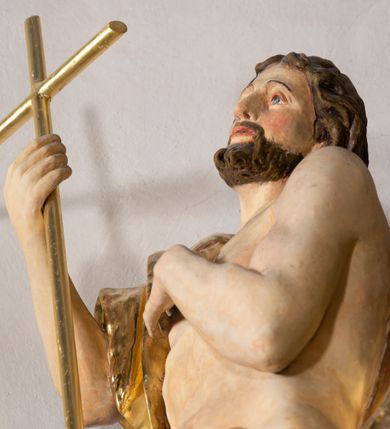 Zdjęcie nr 4: Rzeźba wydrążona z tyłu. Postać Jana Chrzciciela stojąca w kontrapoście z prawą nogą ugiętą, głowa zwrócona w trzech czwartych na lewo. Prawa ręka zgięta w łokciu uniesiona, lewa zgięta z dłonią na piersi. Twarz zakończona ostrym podbródkiem okolonym brodą, rozchylone usta, otwarte oczy, prosty nos, wąskie ciemne brwi, wyraźne rysy z podkreślonymi kośćmi policzkowymi. Na głowie brązowe włosy w postaci loków spływające na plecy. Na prawe ramię zarzucona skóra wielbłąda. Święty w biodrach przepasany tkaniną przewieszoną przez sznur o wyraźnych, obfitych fałdowaniach. Sylwetka z poprawnie i wyraźnie zaznaczoną muskulaturą. Święty trzyma w ręku długi krzyż, a przy nogach leży baranek. Szaty i krzyż złocone, polichromia partii ciała naturalistyczna, figura baranka srebrzona. 