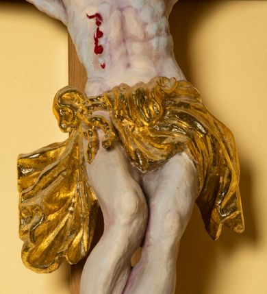 Zdjęcie nr 4: Chrystus przybity do krzyża na wyprężonych ramionach, w silnie wygiętej, esowatej pozie, z głową pochyloną na piersi, przechyloną na prawe ramię. Twarz z prostym nosem, ciemnobrązowymi oczami, lekko rozchylonymi wargami, twarz okolona zarostem i włosami opadającymi na prawe ramię. Klatka piersiowa z zaznaczoną muskulaturą, perizonium przewiązane w pasie sznurem, o fałdach miękko modelowanych, z rozwianym końcem opadającym wzdłuż prawej nogi. Nogi ułożone ukośnie, założone lewa na prawą, przebite jednym gwoździem. Ponad głową Chrystusa titulus z napisem &quot;INRI&quot;.