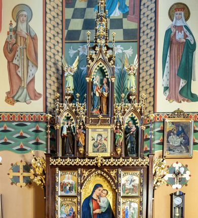 Zdjęcie nr 1: Nastawa ołtarzowa architektoniczna, jednoosiowa, jednokondygnacyjna ze zwieńczeniem, ustawiona na stopniu. Ołtarz prostopadłościenny, drewniany. Antepedium dekorowane trzema płycinami; środkowa w formie wieloliścia z krzyżem w polu. Mensa drewniana, podtrzymywana przez parę kolumn o roślinnych kapitelach. Tabernakulum w formie prostopadłościennej skrzynki, flankowane parą kolumienek na wysokich cokołach podtrzymujących ostrołukową arkadę; na osi kolumn dwa pinakle zwieńczone kwiatonami. Na ściance frontowej drzwiczki ze złoconą płyciną w kształcie stojącego prostokąta, zamkniętego łukiem ostrym z płaskorzeźbionym sercem w polu, obwiedzionym koroną cierniową i promienistą aureolą; dookoła sześć gwiazdek. Na gzymsie tabernakulum płaskorzeźbiona wić roślinna.

Predella ustawiona na niskim cokoliku zdobionym rozetami, powyżej wklęsły wałek oraz płycina w kształcie leżącego prostokąta z rzeźbioną wicią roślinną na czerwonym tle. Nastawa flankowana parą smukłych filarów wspierających wąskie pinakle z kwiatonami i żabkami. Pole główne w formie tryptyku, poszczególne kwatery oddzielone pionowymi płycinami zdobionymi płaskorzeźbioną laską, owiniętą liśćmi stylizowanego akantu. W polu głównym obraz Matki Boskiej z Dzieciątkiem umieszczony w prostokątnej wnęce, zamkniętej łukiem ostrym, podtrzymanym półkolumienkami. W nadłuczach stylizowany astwerk. W lewej kwaterze od dołu obraz przedstawiający Zwiastowanie, powyżej Zaśniecie Matki Boskiej. Z kolei w prawej kwaterze od dołu umieszczony jest obraz „Ofiarowanie Chrystusa”, a wyżej „Wniebowzięcie Najświętszej Marii Panny”. Gzyms kondygnacji ozdobiony jest astwerkiem.

Zwieńczenie trójosiowe, w kształcie trzech ostrołukowych aediculi wspartych zdwojonymi kolumienkami. Pomiędzy osiami podwieszone baldachimy, pod którymi ustawione są na wspornikach dwie rzeźby świętych, z których jeden umieszczony po lewej stronie trzyma księgę, a drugi pióro. Oś środkowa jest znacznie wyższa od bocznych, posadowiona na wysokim cokole, w którym znajduje się wizerunek Matki Boskiej Nieustającej Pomocy, flankowany pilastrami i ze szczytem w formie małego kwiatonu. Powyżej aedicula z głęboką wnęką, w której umieszczone są rzeźby św. Elżbiety i Matki Boskiej przedstawiające scenę Nawiedzenia. Całość zwieńczona dwukondygnacyjnym szczytem z pinaklami, kwiatonami i żabkami. W osi bocznej, lewej w głębokiej wnęce umieszczona jest figura św. Antoniego Padewskiego, a po prawej stronie zwieńczenia figura świętego w stroju  redemptorysty (być może św. Alfons Maria Liguori). Na osi bocznych partii zwieńczenia znajdują sie wsporniki z figurami aniołów. Struktura w odcieniu naturalnego drewna; ornamentyka i profile złocone, detale polichromowane.

