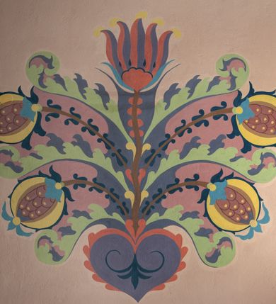 Zdjęcie nr 8: Na dekorację malarską kościoła w Mszanie Dolnej składają się przedstawienia figuralne oraz ornamenty roślinne i fantazyjne. Polichromia ścienna prezbiterium jest bogato dekorowana motywami roślinno-fantazyjnymi. Ościeża okien na ścianie wschodniej zdobią kwiaty chabru, a powyżej na sklepieniu umieszczona jest fantazyjna, promienista gloria z językami ognia, spośród której z szarych obłoków w kształcie płomyków wyłania się Manus Dei. Naroża przęsła malowane są na czarno ze złoconymi falami. Na ścianie północnej prezbiterium w ostrołukowej arkadzie znajduje się przedstawienie Ofiary Melchizedeka, a po przeciwnej stronie Ofiary Abrahama. Całość dopełniają na ościeżach i pozostałych partiach ścian motywy kwiatowe i fantazyjne z przewagą kwiatów chabru i stylizowanych pąków. Tło ścian jest w kolorze beżowym, sklepienie w drugim przęśle prezbiterium malowane jest na niebiesko z analogiczną jak w części wschodniej malowaną promienistą glorią z językami ognia. 

Wschodnia ściana arkady tęczowej podzielona jest na dwie strefy. Dolna część malowana jest na kolor żółty, a w ostrołukowych płycinach umieszczone są dwie sceny: Chrzest Chrystusa po lewej stronie i Kazanie na Górze po prawej stronie. W górnej partii po obu stronach arkady na tle malowanym w kolorze zgaszonego fioletu ukazane są postacie dwunastu aniołów z kwiatami, świecami i kadzielnicami w dłoniach. Na szczycie arkady znajduje się przedstawienie Baranka Bożego, z którego piersi tryska do stojącego obok kielicha krew. Naroża przęsła malowane są na czarno ze złoconymi falami. 

W północnym ramieniu transeptu na ścianie wschodniej umieszczona jest scena Zwiastowania, a po bokach św. Jadwiga Królowa i św. Kinga. Na przeciwnej ścianie znajduje się uskrzydlona główka aniołka podtrzymująca fantazyjny kartusz z napisem: „A SŁOWO / STAŁO SIĘ / CIAŁEM”. W południowym ramieniu transeptu na ścianie wschodniej w ostrołukowej płycinie umieszczone jest przedstawienie św. Józefa z Dzieciątkiem, a po bokach ściany św. Wojciech po lewej stronie i św. Stanisław z Piotrowinem po prawej stronie. Po przeciwnej stronie kaplicy słowa „BĄDŹ WOLA TWOJA” otoczone kwiatami polnego ostu.

Sklepienie na skrzyżowaniu nawy głównej z transeptem pokryte jest złoconymi gwiazdami na niebieskim tle. W centrum umieszczona jest bordowo-niebieska promienista gloria, w środku której na złoconym tle znajują się hierogramy, a na obrzeżach banderole z napisami: „VINCES”, „IN HOC SIGNO”, „VINCES”, „IN HOC SIGNO”. Żebra sklepienie malowane są w pasy w kolorze czerwonym, czarnym i złotym, a na brzegach zdobione fantazyjną, drobną dekoracją.

Nawa główna podzielona jest na dwie strefy. W dolnej na beżowym tle w każdym przęśle nawy znajduje się fantazyjny bukiet kwiatów. Strefy oddzielone są od siebie szerokim pasem w kolorze zgaszonego fioletu, ozdobionego rzędem naprzemiennie białych i żółtych czteropłatkowych kwiatów na ulistnionych gałązkach. W górnej strefie na beżowym tle umieszczone są postacie świętych opatrzone podpisami. Na ścianie północnej od zachodu: „ŚW(IĘTA BARBARA”, „BŁ(OGOSŁAWIONA) SALOMEA”, „ŚW(IĘTA) KATARZYNA” i „BŁ(OGOSŁAWIONA) BRONISŁAWA”. Na ścianie południowej od zachodu: ŚW(IĘTY) ST(ANISŁAW) KOSTKA”, „ŚW(IĘTY) JAN KANTY”, „ŚW(IĘTY) KAZIMIERZ” i „ŚW(IĘTY) FLORIAN”. Ościeża okien w nawie głównej zdobi geometryczna siatka w kolorze zielono-pomarańczowym, a dookoła kwiaty łubinu i bazie. Z kolei przyścienne kolumny, ostrołukowe profilowane przejścia transeptu i nawy głównej zdobią słoneczniki, trójlistne koniczyny oraz pawie oczka.  Dekoracja ornamentalna sklepień w nawie głównej jest podobna, jak w poprzednio opisanych częściach świątyni. 

Na chórze znajduje się przedstawienia św. Franciszka z Asyżu po lewej stronie i św. Cecylii po prawej, a pośrodku słowa „UWIELBIAJ DUSZO MOJA PANA” w fantazyjnej glorii. 
