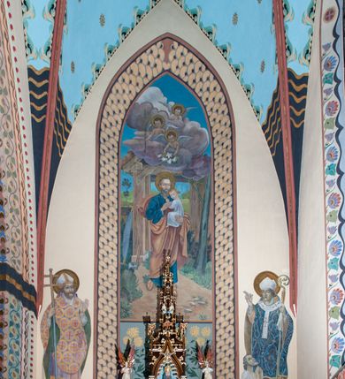 Zdjęcie nr 9: Na dekorację malarską kościoła w Mszanie Dolnej składają się przedstawienia figuralne oraz ornamenty roślinne i fantazyjne. Polichromia ścienna prezbiterium jest bogato dekorowana motywami roślinno-fantazyjnymi. Ościeża okien na ścianie wschodniej zdobią kwiaty chabru, a powyżej na sklepieniu umieszczona jest fantazyjna, promienista gloria z językami ognia, spośród której z szarych obłoków w kształcie płomyków wyłania się Manus Dei. Naroża przęsła malowane są na czarno ze złoconymi falami. Na ścianie północnej prezbiterium w ostrołukowej arkadzie znajduje się przedstawienie Ofiary Melchizedeka, a po przeciwnej stronie Ofiary Abrahama. Całość dopełniają na ościeżach i pozostałych partiach ścian motywy kwiatowe i fantazyjne z przewagą kwiatów chabru i stylizowanych pąków. Tło ścian jest w kolorze beżowym, sklepienie w drugim przęśle prezbiterium malowane jest na niebiesko z analogiczną jak w części wschodniej malowaną promienistą glorią z językami ognia. 

Wschodnia ściana arkady tęczowej podzielona jest na dwie strefy. Dolna część malowana jest na kolor żółty, a w ostrołukowych płycinach umieszczone są dwie sceny: Chrzest Chrystusa po lewej stronie i Kazanie na Górze po prawej stronie. W górnej partii po obu stronach arkady na tle malowanym w kolorze zgaszonego fioletu ukazane są postacie dwunastu aniołów z kwiatami, świecami i kadzielnicami w dłoniach. Na szczycie arkady znajduje się przedstawienie Baranka Bożego, z którego piersi tryska do stojącego obok kielicha krew. Naroża przęsła malowane są na czarno ze złoconymi falami. 

W północnym ramieniu transeptu na ścianie wschodniej umieszczona jest scena Zwiastowania, a po bokach św. Jadwiga Królowa i św. Kinga. Na przeciwnej ścianie znajduje się uskrzydlona główka aniołka podtrzymująca fantazyjny kartusz z napisem: „A SŁOWO / STAŁO SIĘ / CIAŁEM”. W południowym ramieniu transeptu na ścianie wschodniej w ostrołukowej płycinie umieszczone jest przedstawienie św. Józefa z Dzieciątkiem, a po bokach ściany św. Wojciech po lewej stronie i św. Stanisław z Piotrowinem po prawej stronie. Po przeciwnej stronie kaplicy słowa „BĄDŹ WOLA TWOJA” otoczone kwiatami polnego ostu.

Sklepienie na skrzyżowaniu nawy głównej z transeptem pokryte jest złoconymi gwiazdami na niebieskim tle. W centrum umieszczona jest bordowo-niebieska promienista gloria, w środku której na złoconym tle znajują się hierogramy, a na obrzeżach banderole z napisami: „VINCES”, „IN HOC SIGNO”, „VINCES”, „IN HOC SIGNO”. Żebra sklepienie malowane są w pasy w kolorze czerwonym, czarnym i złotym, a na brzegach zdobione fantazyjną, drobną dekoracją.

Nawa główna podzielona jest na dwie strefy. W dolnej na beżowym tle w każdym przęśle nawy znajduje się fantazyjny bukiet kwiatów. Strefy oddzielone są od siebie szerokim pasem w kolorze zgaszonego fioletu, ozdobionego rzędem naprzemiennie białych i żółtych czteropłatkowych kwiatów na ulistnionych gałązkach. W górnej strefie na beżowym tle umieszczone są postacie świętych opatrzone podpisami. Na ścianie północnej od zachodu: „ŚW(IĘTA BARBARA”, „BŁ(OGOSŁAWIONA) SALOMEA”, „ŚW(IĘTA) KATARZYNA” i „BŁ(OGOSŁAWIONA) BRONISŁAWA”. Na ścianie południowej od zachodu: ŚW(IĘTY) ST(ANISŁAW) KOSTKA”, „ŚW(IĘTY) JAN KANTY”, „ŚW(IĘTY) KAZIMIERZ” i „ŚW(IĘTY) FLORIAN”. Ościeża okien w nawie głównej zdobi geometryczna siatka w kolorze zielono-pomarańczowym, a dookoła kwiaty łubinu i bazie. Z kolei przyścienne kolumny, ostrołukowe profilowane przejścia transeptu i nawy głównej zdobią słoneczniki, trójlistne koniczyny oraz pawie oczka.  Dekoracja ornamentalna sklepień w nawie głównej jest podobna, jak w poprzednio opisanych częściach świątyni. 

Na chórze znajduje się przedstawienia św. Franciszka z Asyżu po lewej stronie i św. Cecylii po prawej, a pośrodku słowa „UWIELBIAJ DUSZO MOJA PANA” w fantazyjnej glorii. 
