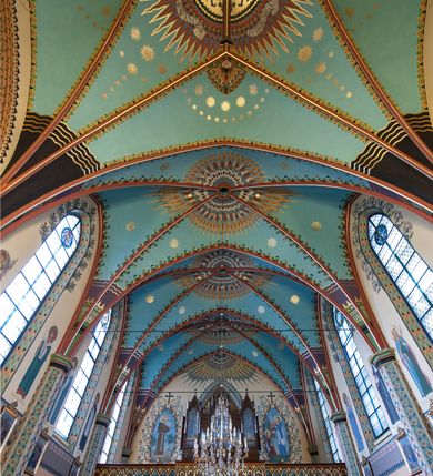 Zdjęcie nr 2: Na dekorację malarską kościoła w Mszanie Dolnej składają się przedstawienia figuralne oraz ornamenty roślinne i fantazyjne. Polichromia ścienna prezbiterium jest bogato dekorowana motywami roślinno-fantazyjnymi. Ościeża okien na ścianie wschodniej zdobią kwiaty chabru, a powyżej na sklepieniu umieszczona jest fantazyjna, promienista gloria z językami ognia, spośród której z szarych obłoków w kształcie płomyków wyłania się Manus Dei. Naroża przęsła malowane są na czarno ze złoconymi falami. Na ścianie północnej prezbiterium w ostrołukowej arkadzie znajduje się przedstawienie Ofiary Melchizedeka, a po przeciwnej stronie Ofiary Abrahama. Całość dopełniają na ościeżach i pozostałych partiach ścian motywy kwiatowe i fantazyjne z przewagą kwiatów chabru i stylizowanych pąków. Tło ścian jest w kolorze beżowym, sklepienie w drugim przęśle prezbiterium malowane jest na niebiesko z analogiczną jak w części wschodniej malowaną promienistą glorią z językami ognia. 

Wschodnia ściana arkady tęczowej podzielona jest na dwie strefy. Dolna część malowana jest na kolor żółty, a w ostrołukowych płycinach umieszczone są dwie sceny: Chrzest Chrystusa po lewej stronie i Kazanie na Górze po prawej stronie. W górnej partii po obu stronach arkady na tle malowanym w kolorze zgaszonego fioletu ukazane są postacie dwunastu aniołów z kwiatami, świecami i kadzielnicami w dłoniach. Na szczycie arkady znajduje się przedstawienie Baranka Bożego, z którego piersi tryska do stojącego obok kielicha krew. Naroża przęsła malowane są na czarno ze złoconymi falami. 

W północnym ramieniu transeptu na ścianie wschodniej umieszczona jest scena Zwiastowania, a po bokach św. Jadwiga Królowa i św. Kinga. Na przeciwnej ścianie znajduje się uskrzydlona główka aniołka podtrzymująca fantazyjny kartusz z napisem: „A SŁOWO / STAŁO SIĘ / CIAŁEM”. W południowym ramieniu transeptu na ścianie wschodniej w ostrołukowej płycinie umieszczone jest przedstawienie św. Józefa z Dzieciątkiem, a po bokach ściany św. Wojciech po lewej stronie i św. Stanisław z Piotrowinem po prawej stronie. Po przeciwnej stronie kaplicy słowa „BĄDŹ WOLA TWOJA” otoczone kwiatami polnego ostu.

Sklepienie na skrzyżowaniu nawy głównej z transeptem pokryte jest złoconymi gwiazdami na niebieskim tle. W centrum umieszczona jest bordowo-niebieska promienista gloria, w środku której na złoconym tle znajują się hierogramy, a na obrzeżach banderole z napisami: „VINCES”, „IN HOC SIGNO”, „VINCES”, „IN HOC SIGNO”. Żebra sklepienie malowane są w pasy w kolorze czerwonym, czarnym i złotym, a na brzegach zdobione fantazyjną, drobną dekoracją.

Nawa główna podzielona jest na dwie strefy. W dolnej na beżowym tle w każdym przęśle nawy znajduje się fantazyjny bukiet kwiatów. Strefy oddzielone są od siebie szerokim pasem w kolorze zgaszonego fioletu, ozdobionego rzędem naprzemiennie białych i żółtych czteropłatkowych kwiatów na ulistnionych gałązkach. W górnej strefie na beżowym tle umieszczone są postacie świętych opatrzone podpisami. Na ścianie północnej od zachodu: „ŚW(IĘTA BARBARA”, „BŁ(OGOSŁAWIONA) SALOMEA”, „ŚW(IĘTA) KATARZYNA” i „BŁ(OGOSŁAWIONA) BRONISŁAWA”. Na ścianie południowej od zachodu: ŚW(IĘTY) ST(ANISŁAW) KOSTKA”, „ŚW(IĘTY) JAN KANTY”, „ŚW(IĘTY) KAZIMIERZ” i „ŚW(IĘTY) FLORIAN”. Ościeża okien w nawie głównej zdobi geometryczna siatka w kolorze zielono-pomarańczowym, a dookoła kwiaty łubinu i bazie. Z kolei przyścienne kolumny, ostrołukowe profilowane przejścia transeptu i nawy głównej zdobią słoneczniki, trójlistne koniczyny oraz pawie oczka.  Dekoracja ornamentalna sklepień w nawie głównej jest podobna, jak w poprzednio opisanych częściach świątyni. 

Na chórze znajduje się przedstawienia św. Franciszka z Asyżu po lewej stronie i św. Cecylii po prawej, a pośrodku słowa „UWIELBIAJ DUSZO MOJA PANA” w fantazyjnej glorii. 
