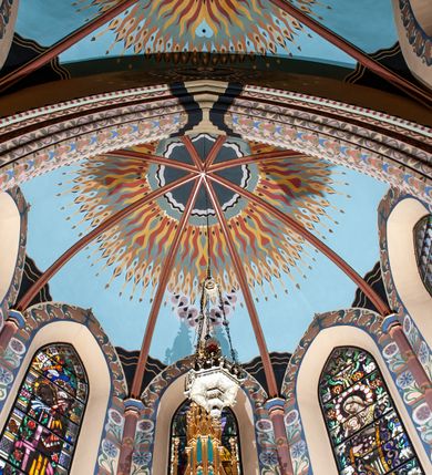 Zdjęcie nr 3: Na dekorację malarską kościoła w Mszanie Dolnej składają się przedstawienia figuralne oraz ornamenty roślinne i fantazyjne. Polichromia ścienna prezbiterium jest bogato dekorowana motywami roślinno-fantazyjnymi. Ościeża okien na ścianie wschodniej zdobią kwiaty chabru, a powyżej na sklepieniu umieszczona jest fantazyjna, promienista gloria z językami ognia, spośród której z szarych obłoków w kształcie płomyków wyłania się Manus Dei. Naroża przęsła malowane są na czarno ze złoconymi falami. Na ścianie północnej prezbiterium w ostrołukowej arkadzie znajduje się przedstawienie Ofiary Melchizedeka, a po przeciwnej stronie Ofiary Abrahama. Całość dopełniają na ościeżach i pozostałych partiach ścian motywy kwiatowe i fantazyjne z przewagą kwiatów chabru i stylizowanych pąków. Tło ścian jest w kolorze beżowym, sklepienie w drugim przęśle prezbiterium malowane jest na niebiesko z analogiczną jak w części wschodniej malowaną promienistą glorią z językami ognia. 

Wschodnia ściana arkady tęczowej podzielona jest na dwie strefy. Dolna część malowana jest na kolor żółty, a w ostrołukowych płycinach umieszczone są dwie sceny: Chrzest Chrystusa po lewej stronie i Kazanie na Górze po prawej stronie. W górnej partii po obu stronach arkady na tle malowanym w kolorze zgaszonego fioletu ukazane są postacie dwunastu aniołów z kwiatami, świecami i kadzielnicami w dłoniach. Na szczycie arkady znajduje się przedstawienie Baranka Bożego, z którego piersi tryska do stojącego obok kielicha krew. Naroża przęsła malowane są na czarno ze złoconymi falami. 

W północnym ramieniu transeptu na ścianie wschodniej umieszczona jest scena Zwiastowania, a po bokach św. Jadwiga Królowa i św. Kinga. Na przeciwnej ścianie znajduje się uskrzydlona główka aniołka podtrzymująca fantazyjny kartusz z napisem: „A SŁOWO / STAŁO SIĘ / CIAŁEM”. W południowym ramieniu transeptu na ścianie wschodniej w ostrołukowej płycinie umieszczone jest przedstawienie św. Józefa z Dzieciątkiem, a po bokach ściany św. Wojciech po lewej stronie i św. Stanisław z Piotrowinem po prawej stronie. Po przeciwnej stronie kaplicy słowa „BĄDŹ WOLA TWOJA” otoczone kwiatami polnego ostu.

Sklepienie na skrzyżowaniu nawy głównej z transeptem pokryte jest złoconymi gwiazdami na niebieskim tle. W centrum umieszczona jest bordowo-niebieska promienista gloria, w środku której na złoconym tle znajują się hierogramy, a na obrzeżach banderole z napisami: „VINCES”, „IN HOC SIGNO”, „VINCES”, „IN HOC SIGNO”. Żebra sklepienie malowane są w pasy w kolorze czerwonym, czarnym i złotym, a na brzegach zdobione fantazyjną, drobną dekoracją.

Nawa główna podzielona jest na dwie strefy. W dolnej na beżowym tle w każdym przęśle nawy znajduje się fantazyjny bukiet kwiatów. Strefy oddzielone są od siebie szerokim pasem w kolorze zgaszonego fioletu, ozdobionego rzędem naprzemiennie białych i żółtych czteropłatkowych kwiatów na ulistnionych gałązkach. W górnej strefie na beżowym tle umieszczone są postacie świętych opatrzone podpisami. Na ścianie północnej od zachodu: „ŚW(IĘTA BARBARA”, „BŁ(OGOSŁAWIONA) SALOMEA”, „ŚW(IĘTA) KATARZYNA” i „BŁ(OGOSŁAWIONA) BRONISŁAWA”. Na ścianie południowej od zachodu: ŚW(IĘTY) ST(ANISŁAW) KOSTKA”, „ŚW(IĘTY) JAN KANTY”, „ŚW(IĘTY) KAZIMIERZ” i „ŚW(IĘTY) FLORIAN”. Ościeża okien w nawie głównej zdobi geometryczna siatka w kolorze zielono-pomarańczowym, a dookoła kwiaty łubinu i bazie. Z kolei przyścienne kolumny, ostrołukowe profilowane przejścia transeptu i nawy głównej zdobią słoneczniki, trójlistne koniczyny oraz pawie oczka.  Dekoracja ornamentalna sklepień w nawie głównej jest podobna, jak w poprzednio opisanych częściach świątyni. 

Na chórze znajduje się przedstawienia św. Franciszka z Asyżu po lewej stronie i św. Cecylii po prawej, a pośrodku słowa „UWIELBIAJ DUSZO MOJA PANA” w fantazyjnej glorii. 
