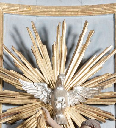 Zdjęcie nr 5: Antyambona złączona z chrzcielnicą. Stopa chrzcielnicy na planie kwadratu, profilowana. Trzon czteroboczny, zwężający się ku górze, w narożach od frontu ujęty listwami. Czara w formie odwróconego, ściętego stożka, z wywiniętą krawędzią. Od spodu opięta pierścieniem i silnie uproszczonym, stylizowanym, żłobkowanym lambrekinem. Pokrywa w formie profilowanego, ściętego stożka, zwieńczonego akantem i szyszką. We wnętrzu czary miedziana misa oraz fragment drewnianej pokrywy z rozetą. Antyambona przyścienna, o wklęsłym licu, na cokole, ujęta filarami podtrzymującymi profilowany gzyms, dekorowanymi płycinami. Pośrodku wspornik w formie wybrzuszonego stożka, o ściętym wierzchołku z grupą rzeźbiarską Chrzest Chrystusa. Powyżej zaplecek ujęty pilastrami, dźwigającymi spływ wolutowe; po bokach udrapowana tkanina. W polu środkowym płycina z rzeźbioną gołębicą Ducha Świętego na tle glorii promienistej. Baldachim na planie odcinka koła, z wyłamującym się gzymsem, dekorowany podwieszonym lambrekinem, zwężający się ku górze, zakończony rokokowym wazonem płomienistym. Struktura marmoryzowana w kolorze jasnoniebieskim, cokół, gzyms i profile jasnoróżowe, dekoracja złocona i srebrzona.