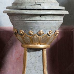 Zdjęcie nr 1: Antyambona złączona z chrzcielnicą. Stopa chrzcielnicy na planie kwadratu, profilowana. Trzon czteroboczny, zwężający się ku górze, w narożach od frontu ujęty listwami. Czara w formie odwróconego, ściętego stożka, z wywiniętą krawędzią. Od spodu opięta pierścieniem i silnie uproszczonym, stylizowanym, żłobkowanym lambrekinem. Pokrywa w formie profilowanego, ściętego stożka, zwieńczonego akantem i szyszką. We wnętrzu czary miedziana misa oraz fragment drewnianej pokrywy z rozetą. Antyambona przyścienna, o wklęsłym licu, na cokole, ujęta filarami podtrzymującymi profilowany gzyms, dekorowanymi płycinami. Pośrodku wspornik w formie wybrzuszonego stożka, o ściętym wierzchołku z grupą rzeźbiarską Chrzest Chrystusa. Powyżej zaplecek ujęty pilastrami, dźwigającymi spływ wolutowe; po bokach udrapowana tkanina. W polu środkowym płycina z rzeźbioną gołębicą Ducha Świętego na tle glorii promienistej. Baldachim na planie odcinka koła, z wyłamującym się gzymsem, dekorowany podwieszonym lambrekinem, zwężający się ku górze, zakończony rokokowym wazonem płomienistym. Struktura marmoryzowana w kolorze jasnoniebieskim, cokół, gzyms i profile jasnoróżowe, dekoracja złocona i srebrzona.