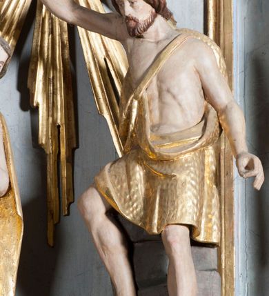 Zdjęcie nr 2: Grupa rzeźbiarska przedstawiająca scenę Chrztu Chrystusa. Rzeźby pełne, całopostaciowe. Po prawej stronie, na blikach skalnych św. Jan Chrzciciel zwrócony w prawo, z prawą nogą ustawioną wyżej, z uniesioną prawą ręką, w której trzyma muszlę z wodą, którą wylewa nad głową Chrystusa. Twarz ma pociągłą, szczupłą, okoloną krótką brodą, włosy półdługie, opadające na kark. Ubrany w osłaniający biodra płaszcz ze skóry, podtrzymywany przez taśmę przewiązaną przez lewe ramię. Po przeciwnej stronie figura Chrystusa zwróconego w trzech czwartych w lewo, w kontrapoście, delikatnie pochylonego z dłońmi skrzyżowanymi na piersi. Twarz pociągła, okolona krótką brodą, włosy długie, opadające na plecy. Na ramiona ma zarzucony płaszcz, biodra przepasane drapowaną tkaniną sięgającą kostek, tors nagi. W tle dużej wielkości gołębica Ducha Świętego na tle glorii promienistej. W odsłoniętych partiach ciała polichromia naturalistyczna, szaty złocone. 