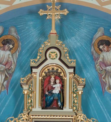 Zdjęcie nr 4: Nastawa ołtarzowa jednokondygnacyjna ze zwieńczeniem, trójosiowa, na cokole. Mensa prostopadłościenna, murowana, w drewnianej obudowie, z kamiennym blatem. Antepedium podzielone na trzy pola, wydzielone czterema kolumienkami. Zewnętrzne płyciny w formie leżącego prostokąta, z płaskorzeźbionymi przedstawieniami po lewej stronie ofiara Melchizedeka, po prawej ofiara Abrahama. W polu środkowym płycina w formie kwadratu, z stylizowanym maswerkowaniem i równoramiennym krzyżem pośrodku oraz rozetami w narożach. Na mensie tabernakulum na wysokiej, prostopadłościennej podstawie, w której znajdują się drzwiczki dekorowane hostią w glorii, flankowane pilastrami z dekoracją  ornamentem arabeskowym. Na osi tron wystawienia w formie niszy ujęty parą smukłych kolumienek podtrzymujących szerokie belkowanie przechodzące nad niszą w łuk. Gzyms wieńczy ornament roślinny, na środku na cokole postać baranka w glorii na księdze z siedmioma pieczęciami. Predella podzielona na trzy pola z występującymi do przodu dwiema niszami z figurami klęczących aniołów. W polach zewnętrznych trzy arkadki z płaskorzeźbionymi przedstawieniami świętych. W polu środkowym tabernakulum flankowane przed dwie arkadki z przedstawieniami świętych. Pierwsza kondygnacja utworzona z trzech arkad wydzielonych kolumnami, oś środkowa wyższa od bocznych. W polu środkowym obraz z przedstawieniem Najświętszego Serca Jezusa, w profilowanej ramie; archiwolta ujęta kolumienkami. Całość zamknięta silnie wysuniętym gzymsem o fantazyjnej linii. W osiach bocznych aedicule z posągami św. Piotra i św. Pawła, zwieńczone daszkiem z latarniami. Kondygnacja flankowana wielobocznymi wspornikami z figurami aniołów. Zwieńczenie w formie aediculi ujętej kolumienkami we wnękach oraz otwartymi półarkadami. Całość zamknięta gzymsem o fantazyjnej linii oraz krzyżem. W niszy figura Matki Boskiej z Dzieciątkiem. Cokoły zdobione płycinami z malowaną i złoconą dekoracja roślinną. Rama obrazu w polu środkowym dekorowana ornamentem roślinno-geometrycznym; archiwolta ornamentem roślinnym w formie liści. Powyżej płycina w kształcie łuku odcinkowego z rzeźbionym ornamentem roślinnym. Archiwolty arkad na osiach bocznych dekorowane ornamentem geometrycznym i stylizowanymi żabkami, w przyłuczach rozety; latarnie zdobione ornamentem roślinnym i stylizowanymi żabkami. Struktura polichromowana w kolorze kości słoniowej i szarym; płyciny i profilowania w kolorze czerwonym oraz zielonym, elementy dekoracyjne złocone.