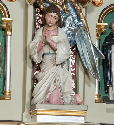 Zdjęcie nr 21: Nastawa ołtarzowa jednokondygnacyjna ze zwieńczeniem, trójosiowa, na cokole. Mensa prostopadłościenna, murowana, w drewnianej obudowie, z kamiennym blatem. Antepedium podzielone na trzy pola, wydzielone czterema kolumienkami. Zewnętrzne płyciny w formie leżącego prostokąta, z płaskorzeźbionymi przedstawieniami po lewej stronie ofiara Melchizedeka, po prawej ofiara Abrahama. W polu środkowym płycina w formie kwadratu, z stylizowanym maswerkowaniem i równoramiennym krzyżem pośrodku oraz rozetami w narożach. Na mensie tabernakulum na wysokiej, prostopadłościennej podstawie, w której znajdują się drzwiczki dekorowane hostią w glorii, flankowane pilastrami z dekoracją  ornamentem arabeskowym. Na osi tron wystawienia w formie niszy ujęty parą smukłych kolumienek podtrzymujących szerokie belkowanie przechodzące nad niszą w łuk. Gzyms wieńczy ornament roślinny, na środku na cokole postać baranka w glorii na księdze z siedmioma pieczęciami. Predella podzielona na trzy pola z występującymi do przodu dwiema niszami z figurami klęczących aniołów. W polach zewnętrznych trzy arkadki z płaskorzeźbionymi przedstawieniami świętych. W polu środkowym tabernakulum flankowane przed dwie arkadki z przedstawieniami świętych. Pierwsza kondygnacja utworzona z trzech arkad wydzielonych kolumnami, oś środkowa wyższa od bocznych. W polu środkowym obraz z przedstawieniem Najświętszego Serca Jezusa, w profilowanej ramie; archiwolta ujęta kolumienkami. Całość zamknięta silnie wysuniętym gzymsem o fantazyjnej linii. W osiach bocznych aedicule z posągami św. Piotra i św. Pawła, zwieńczone daszkiem z latarniami. Kondygnacja flankowana wielobocznymi wspornikami z figurami aniołów. Zwieńczenie w formie aediculi ujętej kolumienkami we wnękach oraz otwartymi półarkadami. Całość zamknięta gzymsem o fantazyjnej linii oraz krzyżem. W niszy figura Matki Boskiej z Dzieciątkiem. Cokoły zdobione płycinami z malowaną i złoconą dekoracja roślinną. Rama obrazu w polu środkowym dekorowana ornamentem roślinno-geometrycznym; archiwolta ornamentem roślinnym w formie liści. Powyżej płycina w kształcie łuku odcinkowego z rzeźbionym ornamentem roślinnym. Archiwolty arkad na osiach bocznych dekorowane ornamentem geometrycznym i stylizowanymi żabkami, w przyłuczach rozety; latarnie zdobione ornamentem roślinnym i stylizowanymi żabkami. Struktura polichromowana w kolorze kości słoniowej i szarym; płyciny i profilowania w kolorze czerwonym oraz zielonym, elementy dekoracyjne złocone.