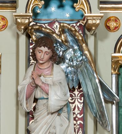 Zdjęcie nr 22: Nastawa ołtarzowa jednokondygnacyjna ze zwieńczeniem, trójosiowa, na cokole. Mensa prostopadłościenna, murowana, w drewnianej obudowie, z kamiennym blatem. Antepedium podzielone na trzy pola, wydzielone czterema kolumienkami. Zewnętrzne płyciny w formie leżącego prostokąta, z płaskorzeźbionymi przedstawieniami po lewej stronie ofiara Melchizedeka, po prawej ofiara Abrahama. W polu środkowym płycina w formie kwadratu, z stylizowanym maswerkowaniem i równoramiennym krzyżem pośrodku oraz rozetami w narożach. Na mensie tabernakulum na wysokiej, prostopadłościennej podstawie, w której znajdują się drzwiczki dekorowane hostią w glorii, flankowane pilastrami z dekoracją  ornamentem arabeskowym. Na osi tron wystawienia w formie niszy ujęty parą smukłych kolumienek podtrzymujących szerokie belkowanie przechodzące nad niszą w łuk. Gzyms wieńczy ornament roślinny, na środku na cokole postać baranka w glorii na księdze z siedmioma pieczęciami. Predella podzielona na trzy pola z występującymi do przodu dwiema niszami z figurami klęczących aniołów. W polach zewnętrznych trzy arkadki z płaskorzeźbionymi przedstawieniami świętych. W polu środkowym tabernakulum flankowane przed dwie arkadki z przedstawieniami świętych. Pierwsza kondygnacja utworzona z trzech arkad wydzielonych kolumnami, oś środkowa wyższa od bocznych. W polu środkowym obraz z przedstawieniem Najświętszego Serca Jezusa, w profilowanej ramie; archiwolta ujęta kolumienkami. Całość zamknięta silnie wysuniętym gzymsem o fantazyjnej linii. W osiach bocznych aedicule z posągami św. Piotra i św. Pawła, zwieńczone daszkiem z latarniami. Kondygnacja flankowana wielobocznymi wspornikami z figurami aniołów. Zwieńczenie w formie aediculi ujętej kolumienkami we wnękach oraz otwartymi półarkadami. Całość zamknięta gzymsem o fantazyjnej linii oraz krzyżem. W niszy figura Matki Boskiej z Dzieciątkiem. Cokoły zdobione płycinami z malowaną i złoconą dekoracja roślinną. Rama obrazu w polu środkowym dekorowana ornamentem roślinno-geometrycznym; archiwolta ornamentem roślinnym w formie liści. Powyżej płycina w kształcie łuku odcinkowego z rzeźbionym ornamentem roślinnym. Archiwolty arkad na osiach bocznych dekorowane ornamentem geometrycznym i stylizowanymi żabkami, w przyłuczach rozety; latarnie zdobione ornamentem roślinnym i stylizowanymi żabkami. Struktura polichromowana w kolorze kości słoniowej i szarym; płyciny i profilowania w kolorze czerwonym oraz zielonym, elementy dekoracyjne złocone.