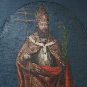 Zdjęcie nr 1: Obraz z przedstawieniem św. Wojciecha w kształcie stojącego prostokąta w prostej, profilowanej ramie. Święty ukazany całopostaciowo, frontalnie. Ma pociągłą twarz o jasnej karnacji, niewielki nos, małe, pełne usta i ciemne, wyraziste oczy. Twarz ma okoloną ciemnobrązowymi włosami i brodą sięgającą dekoltu. Święty Wojciech został przedstawiony w stroju pontyfikalnym złożonym z ciemnozielonej, długiej sutanny, komży wykończonej pod szyją koronką, złotej kapy dekorowanej wzorem floralnym i szeroką bordiurą z naszytymi perłami i kamieniami oraz podbitej purpurą. Na kapę nałożony ma paliusz, a na głowie złotą infułę. Święty w lewej ręce trzyma podwójny krzyż misyjny, w prawej liść palmowy z pozwijanymi końcami. Z lewej strony kompozycji u dołu wielopostaciowa scena męczeństwa świętego, reszta tła jednolita – ciemnoniebieska. Obraz utrzymany w ciemnej kolorystyce, rysunek wyrazisty.