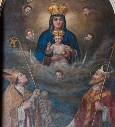 Zdjęcie nr 1: Obraz w kształcie stojącego prostokąta zamkniętego od góry łukiem półkolistym z przedstawieniem Matki Boskiej z Dzieciątkiem tronującej między świętymi. Madonna ukazana frontalnie, w półpostaci, z podtrzymywanym obiema rękami Dzieciątkiem Jezus na kolanach. Ma owalną twarz z podłużnym nosem, drobnymi ustami i dużymi, wyraźnie zaznaczonymi oczami. Dzieciątko spogląda na widza, prawą rękę unosi w geście błogosławieństwa, w lewej trzyma jabłko królewskie. Ma owalną, delikatną twarz z wąskim nosem, małymi ustami i okrągłymi oczami, otoczoną puklami jasnych włosów. Matka Boska jest ubrana w widoczną tylko przy nadgarstkach czerwoną suknię i obszerny, zarzucony na głowę  niebieski płaszcz zdobiony przy brzegu rzędem pereł oraz złotą taśmą. Dzieciątko ubrane w jasnoróżową sukienkę przewiązaną w pasie. Na głowach postaci zamknięte korony zdobione kamieniami szlachetnymi, a wokół uskrzydlone główki anielskie. W dolnej partii obrazu klęczą, spoglądając na Marię z Jezusem św. Stanisław po lewej stronie i św. Wojciech po prawej. Obaj mają nad głowami nimby. Święty Stanisław  w lewej ręce trzyma pastorał, a prawą ma uniesioną na wysokości mostka. Jest ubrany w strój biskupi: infułę, albę, humerał, stułę, na to założoną ma obszerną, złotą kapę, która spięta pod szyją ozdobną fibulą okrywa ramiona i spływa do ziemi, wywijając się obszernymi fałdami. Za nim stoi Piotrowin ukazany jako starszy, modlący się mężczyzna okryty w pasie białą tkaniną. Święty Wojciech prawą rękę wyciąga przed siebie, a w lewej trzyma krzyż misyjny. Jest ubrany w białą albę, czerwoną stułę, której końce są widoczne na wysokości kolan, czerwony ornat o wykroju w szpic dekorowany złotą kolumną. Pod szyją ma biały humerał, na głowie białą infułę zdobioną złotymi paskami i krzyżami greckimi. W tle skłębione obłoki, szaro-niebieskie na wysokości świętych, wyżej gęste, ujmujące od dołu Marię z Dzieciątkiem, w górnej partii przechodzą w brunatne, rozświetlone za plecami tronujących. 