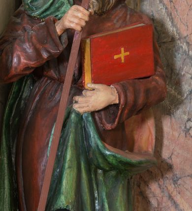 Zdjęcie nr 4: Rzeźba drążona, na cokole. Święty Cyryl został ukazany całopostaciowo, zwrócony nieznacznie w lewo z korpusem przechylonym na tę stronę, w kontrapoście. Ma owalną twarz o jasnej karnacji, wysokim czole, niebieskich oczach o kącikach zewnętrznych opadających w dół, niewielkim prostym nosie i małych ustach; falowana, jasnobrązowa broda opada mu na pierś. Jest ubrany w długi ciemnoczerwony habit przewiązany w pasie, z kapturem założonym na głowę. Habit opada do ziemi, łamiąc się w grube fałdy, spod niego wystają fragmenty butów. Na habit ma zarzucony na prawe ramię, udrapowany płaszcz w kolorze zieleni. W prawej dłoni Cyryl trzyma krzyż misyjny, lewą podtrzymuje rąbek płaszcza i księgę w czerwonej oprawie ze złotym krzyżem. Polichromia w partiach ciała naturalistyczna. 