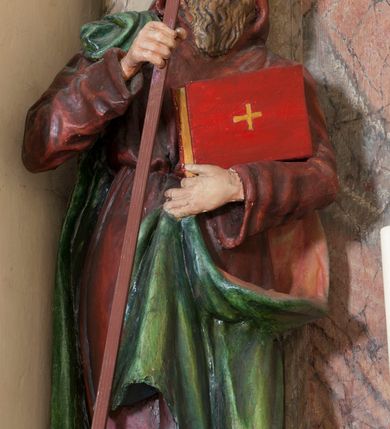 Zdjęcie nr 1: Rzeźba drążona, na cokole. Święty Cyryl został ukazany całopostaciowo, zwrócony nieznacznie w lewo z korpusem przechylonym na tę stronę, w kontrapoście. Ma owalną twarz o jasnej karnacji, wysokim czole, niebieskich oczach o kącikach zewnętrznych opadających w dół, niewielkim prostym nosie i małych ustach; falowana, jasnobrązowa broda opada mu na pierś. Jest ubrany w długi ciemnoczerwony habit przewiązany w pasie, z kapturem założonym na głowę. Habit opada do ziemi, łamiąc się w grube fałdy, spod niego wystają fragmenty butów. Na habit ma zarzucony na prawe ramię, udrapowany płaszcz w kolorze zieleni. W prawej dłoni Cyryl trzyma krzyż misyjny, lewą podtrzymuje rąbek płaszcza i księgę w czerwonej oprawie ze złotym krzyżem. Polichromia w partiach ciała naturalistyczna. 