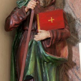 Zdjęcie nr 1: Rzeźba drążona, na cokole. Święty Cyryl został ukazany całopostaciowo, zwrócony nieznacznie w lewo z korpusem przechylonym na tę stronę, w kontrapoście. Ma owalną twarz o jasnej karnacji, wysokim czole, niebieskich oczach o kącikach zewnętrznych opadających w dół, niewielkim prostym nosie i małych ustach; falowana, jasnobrązowa broda opada mu na pierś. Jest ubrany w długi ciemnoczerwony habit przewiązany w pasie, z kapturem założonym na głowę. Habit opada do ziemi, łamiąc się w grube fałdy, spod niego wystają fragmenty butów. Na habit ma zarzucony na prawe ramię, udrapowany płaszcz w kolorze zieleni. W prawej dłoni Cyryl trzyma krzyż misyjny, lewą podtrzymuje rąbek płaszcza i księgę w czerwonej oprawie ze złotym krzyżem. Polichromia w partiach ciała naturalistyczna. 