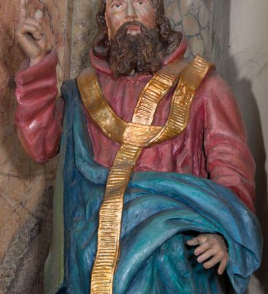 Zdjęcie nr 6: Rzeźba drążona, na cokole. Święty Metody został ukazany całopostaciowo, frontalnie, z głową zwróconą nieznacznie w lewo. Ma prostokątną twarz o jasnej karnacji, wysokim czole, brązowych oczach, prostym nosie i małych ustach. Falowana, ciemnobrązowa, rozdzielająca się w dwa pukle broda opada mu na pierś, a falowane włosy na ramiona i plecy. Jest ubrany w długi, ciemnoczerwony habit przewiązany w pasie, z kapturem wyłożonym na plecy. Habit opada do ziemi, łamiąc się w grube fałdy, na nim ma przewieszony złoty paliusz. Spod habitu wystają fragmenty odzianych w sandały stóp. Na habit ma zarzucony przez prawe ramię, udrapowany płaszcz w kolorze niebieskim. Metody unosi prawą dłoń w geście błogosławieństwa, lewą podtrzymuje fałdy płaszcza. Polichromia w partiach ciała naturalistyczna.