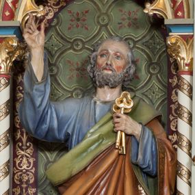 Zdjęcie nr 1: Rzeźba pełna na cokole przedstawiająca św. Piotra ukazanego w całej postaci, frontalnie, z głową przechyloną nieznacznie na lewo. Święty prawą rękę unosi w geście błogosławieństwa, w lewej trzyma dwa klucze. Ma prostokątną twarz z niebieskimi szeroko otwartymi oczami, prostym nosem oraz wąskimi, czerwonymi ustami. Okalają ją siwe włosy, które spływając falami zasłaniają uszy oraz siwa, krótka broda i wąsy. Jest ubrany w niebieską tunikę z szerokimi rękawami i złotą lamówką oraz podbity zielonym materiałem brązowy płaszcz, dekorowany złotą lamówką i bordiurą z ornamentem roślinnym tej samej barwy, przechodzący przez lewy bark i wokół prawego biodra. Tkaniny gną się w grube fałdy. W partiach ciała polichromia naturalistyczna, klucze złocone. 