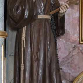 Zdjęcie nr 1: Rzeźba pełna przedstawiająca stojącego św. Franciszka. Święty ukazany frontalnie, z głową lekko pochyloną. Oczy ma opuszczone, nos prosty, usta wąskie; na głowie tonsurę, włosy ciemne, broda dzieli się w dwa pukle. Święty jest ubrany w brązowy habit franciszkański przepasany jasnym sznurem z węzłami, za który ma zatknięty różaniec. Prawą rękę unosi w geście błogosławieństwa, w lewej trzyma krucyfiks. Polichromia w partiach ciała naturalistyczna.