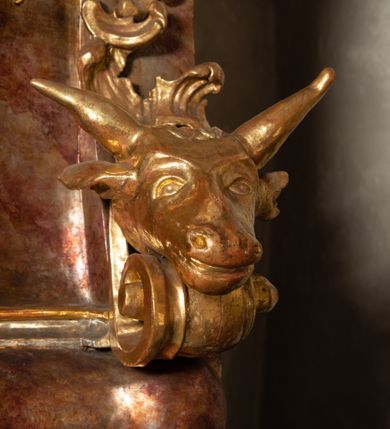 Zdjęcie nr 16: Ambona przyścienna, wisząca, z wejściem od tyłu dwubiegowymi schodami z podestem. Kosz na rzucie owalu o wklęsłych ściankach bocznych i wypukłej frontowej, na wypukłym cokole zdobionym od frontu płaskorzeźbionym motywem rocaille’u. U spodu kosza pięć kabłąków dekorowanych u góry palmetami i fragmentami rocaille’ów, zakończonych zwisem w formie winnego grona. Ścianki kosza opięte wklęsłym pilastrami; od frontu z figurami św. Jana i św. Mateusza siedzących na obłokach, trzymających otwarte księgi z napisem: OVI EX DEO EST VERBA DEI AUDIT / PROPTEREA VOS NON AUDITIS, QVIA EX DEO NON ESTIS. Joanne 8,47; oraz: ERAT ENIM / DOCENS EOS / SICUT PO=/TESTATEM /HABENS / ET NON / SICUT / SCRIBAE / EORUM / ET PHARI=/SAEI. Mat 7,18; na tle pozostałych pilastrów symbole ewangelistów: orzeł trzymający w ‘szponach kałamarz oraz głowa wołu. Ścianki w polach dekorowane rocaille’ami, frontowa z różanymi gałązkami. Kosz zwieńczony profilowanym gzymsem, występującym nad pilastrami. Na zaplecku obraz Szymona Kawalskiego Rozesłanie Apostołów, w kształcie leżącego prostokąta, w profilowanej, złoconej ramie, ujęty uszami utworzonymi z motywów rocaille’ów. Baldachim powtarza rzut kosza, wsparty na belkowaniu dekorowanym palmetami i rocaille’ami w partii fryzu, z podwieszonym lambrekinem. Powyżej ażurowa konstrukcja z wolut dekorowanych rocaille’ami, zbliżona do korony, otaczająca półpostać Chrystusa trzymającego jabłko królewskie i laskę pasterską. U spodu baldachimu podwieszona Gołębica Ducha Świętego w glorii. Struktura marmoryzowana laserunkowo, profile srebrzone, ornamenty złocone.