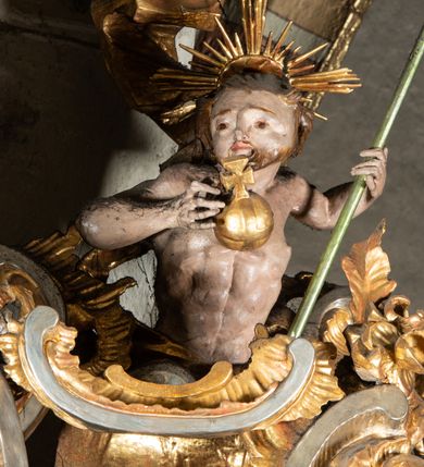 Zdjęcie nr 11: Ambona przyścienna, wisząca, z wejściem od tyłu dwubiegowymi schodami z podestem. Kosz na rzucie owalu o wklęsłych ściankach bocznych i wypukłej frontowej, na wypukłym cokole zdobionym od frontu płaskorzeźbionym motywem rocaille’u. U spodu kosza pięć kabłąków dekorowanych u góry palmetami i fragmentami rocaille’ów, zakończonych zwisem w formie winnego grona. Ścianki kosza opięte wklęsłym pilastrami; od frontu z figurami św. Jana i św. Mateusza siedzących na obłokach, trzymających otwarte księgi z napisem: OVI EX DEO EST VERBA DEI AUDIT / PROPTEREA VOS NON AUDITIS, QVIA EX DEO NON ESTIS. Joanne 8,47; oraz: ERAT ENIM / DOCENS EOS / SICUT PO=/TESTATEM /HABENS / ET NON / SICUT / SCRIBAE / EORUM / ET PHARI=/SAEI. Mat 7,18; na tle pozostałych pilastrów symbole ewangelistów: orzeł trzymający w ‘szponach kałamarz oraz głowa wołu. Ścianki w polach dekorowane rocaille’ami, frontowa z różanymi gałązkami. Kosz zwieńczony profilowanym gzymsem, występującym nad pilastrami. Na zaplecku obraz Szymona Kawalskiego Rozesłanie Apostołów, w kształcie leżącego prostokąta, w profilowanej, złoconej ramie, ujęty uszami utworzonymi z motywów rocaille’ów. Baldachim powtarza rzut kosza, wsparty na belkowaniu dekorowanym palmetami i rocaille’ami w partii fryzu, z podwieszonym lambrekinem. Powyżej ażurowa konstrukcja z wolut dekorowanych rocaille’ami, zbliżona do korony, otaczająca półpostać Chrystusa trzymającego jabłko królewskie i laskę pasterską. U spodu baldachimu podwieszona Gołębica Ducha Świętego w glorii. Struktura marmoryzowana laserunkowo, profile srebrzone, ornamenty złocone.