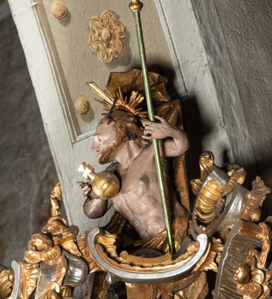 Zdjęcie nr 12: Ambona przyścienna, wisząca, z wejściem od tyłu dwubiegowymi schodami z podestem. Kosz na rzucie owalu o wklęsłych ściankach bocznych i wypukłej frontowej, na wypukłym cokole zdobionym od frontu płaskorzeźbionym motywem rocaille’u. U spodu kosza pięć kabłąków dekorowanych u góry palmetami i fragmentami rocaille’ów, zakończonych zwisem w formie winnego grona. Ścianki kosza opięte wklęsłym pilastrami; od frontu z figurami św. Jana i św. Mateusza siedzących na obłokach, trzymających otwarte księgi z napisem: OVI EX DEO EST VERBA DEI AUDIT / PROPTEREA VOS NON AUDITIS, QVIA EX DEO NON ESTIS. Joanne 8,47; oraz: ERAT ENIM / DOCENS EOS / SICUT PO=/TESTATEM /HABENS / ET NON / SICUT / SCRIBAE / EORUM / ET PHARI=/SAEI. Mat 7,18; na tle pozostałych pilastrów symbole ewangelistów: orzeł trzymający w ‘szponach kałamarz oraz głowa wołu. Ścianki w polach dekorowane rocaille’ami, frontowa z różanymi gałązkami. Kosz zwieńczony profilowanym gzymsem, występującym nad pilastrami. Na zaplecku obraz Szymona Kawalskiego Rozesłanie Apostołów, w kształcie leżącego prostokąta, w profilowanej, złoconej ramie, ujęty uszami utworzonymi z motywów rocaille’ów. Baldachim powtarza rzut kosza, wsparty na belkowaniu dekorowanym palmetami i rocaille’ami w partii fryzu, z podwieszonym lambrekinem. Powyżej ażurowa konstrukcja z wolut dekorowanych rocaille’ami, zbliżona do korony, otaczająca półpostać Chrystusa trzymającego jabłko królewskie i laskę pasterską. U spodu baldachimu podwieszona Gołębica Ducha Świętego w glorii. Struktura marmoryzowana laserunkowo, profile srebrzone, ornamenty złocone.