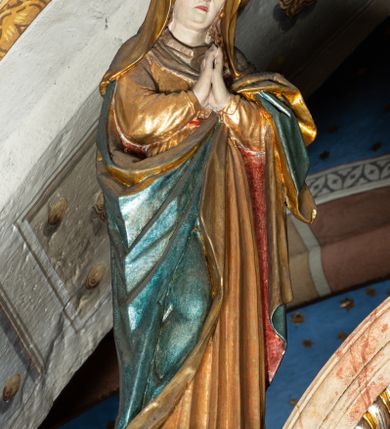 Zdjęcie nr 3: Belka profilowana, o formie pełnego belkowania, wygięta faliście, pośrodku wyłamana łukiem półkolistym nadwieszonym. Od frontu fryz dekorowany akantem i rozetami; od strony prezbiterium data: 1770; od spodu dekorowana rozetami. Na belce Grupa Ukrzyżowania. Rzeźby pełnoplastyczne, polichromowane. Pośrodku krzyż z figurą martwego Chrystusa. Ciało w lekkim zwisie, o szeroko rozłożonych ramionach. Kolana delikatnie ugięte, stopy przebite jednym gwoździem, założone prawa na lewą. Ciało wychudzone, smukłe, o podkreślonej muskulaturze, z zaznaczonymi śladami męki. Twarz pociągła, szczupła, oczy zamknięte; okolona zarostem. Włosy długie, opadające na ramiona. Na głowie korona cierniowa. Perizonium krótkie, ściśle opinające biodra, delikatnie drapowanie, ze zwisem tkaniny przy prawym boku. Na górnej belce krzyża titulus w formie kartusza z literami: INRI. U dołu krzyża klęcząca św. Maria Magdalena zwróconej en trois quarts w lewo, z głową skierowaną ku górze. Lewą ręką przytrzymuje stopę Chrystusa, prawa wyciągnięta przed siebie. Włosy upięte z tyłu głowy. Ubrana w bogatą suknię z gorsetem i dekoracyjnych rękawach oraz płaszcz zarzucony na ramiona. Po prawej stronie krzyża Matki Boska, ukazana frontalnie, z delikatnie pochylona głową i dłońmi złożonymi w geście modlitwy. Twarz pociągła, z uwypuklonym podbródkiem. Maria ubrana w suknię oraz płaszcz przewiązany na lewym ramieniu. Na głowie welon. Po lewej stronie krzyża św. Jan Ewangelista, ukazany en face, z głową skierowaną ku górze i dłońmi skrzyżowanymi na piersi. Twarz pociągła o młodzieńczych rysach, włosy długie, kręcone. Ubrany w długa tunikę przewiązaną w talii oraz płaszcz przewiązany na lewym ramieniu. Polichromia naturalistyczna w odsłoniętych partiach ciała, szaty złocone z laserunkiem.